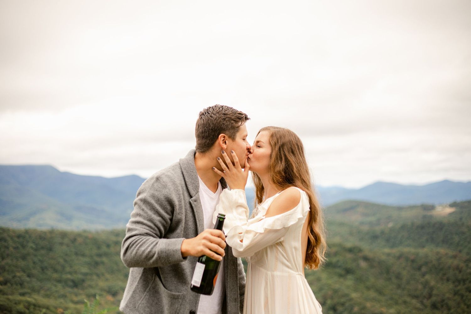 Couple sharing a romantic moment with champagne against a mountain backdrop.