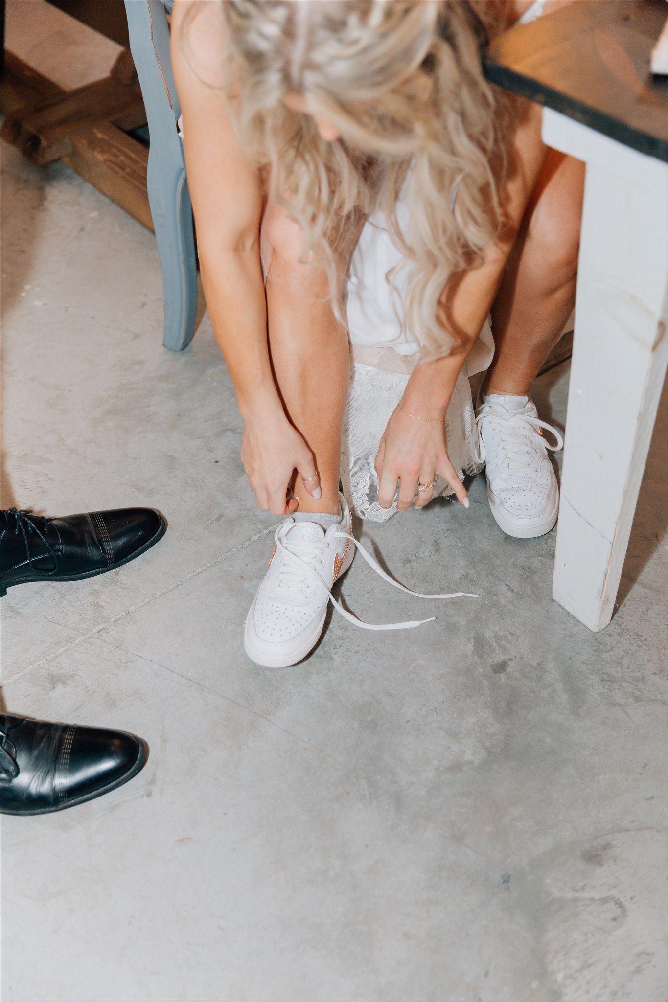 A person changing into white sneakers while wearing a formal dress.