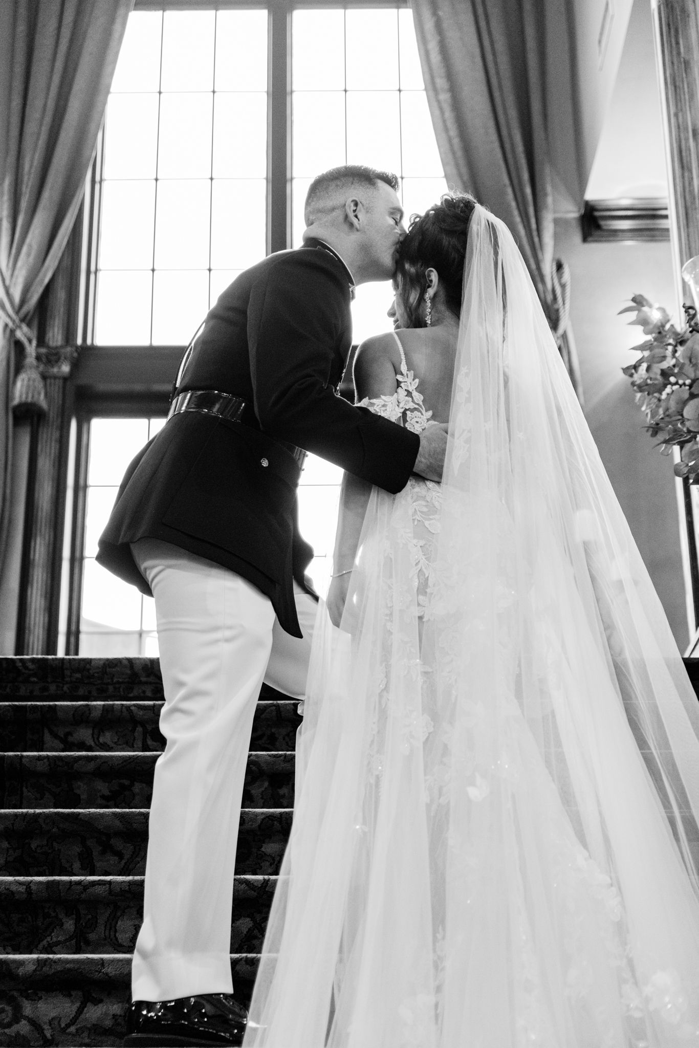 A series of black and white wedding photos showing a couple in progressive poses on an elegant staircase.