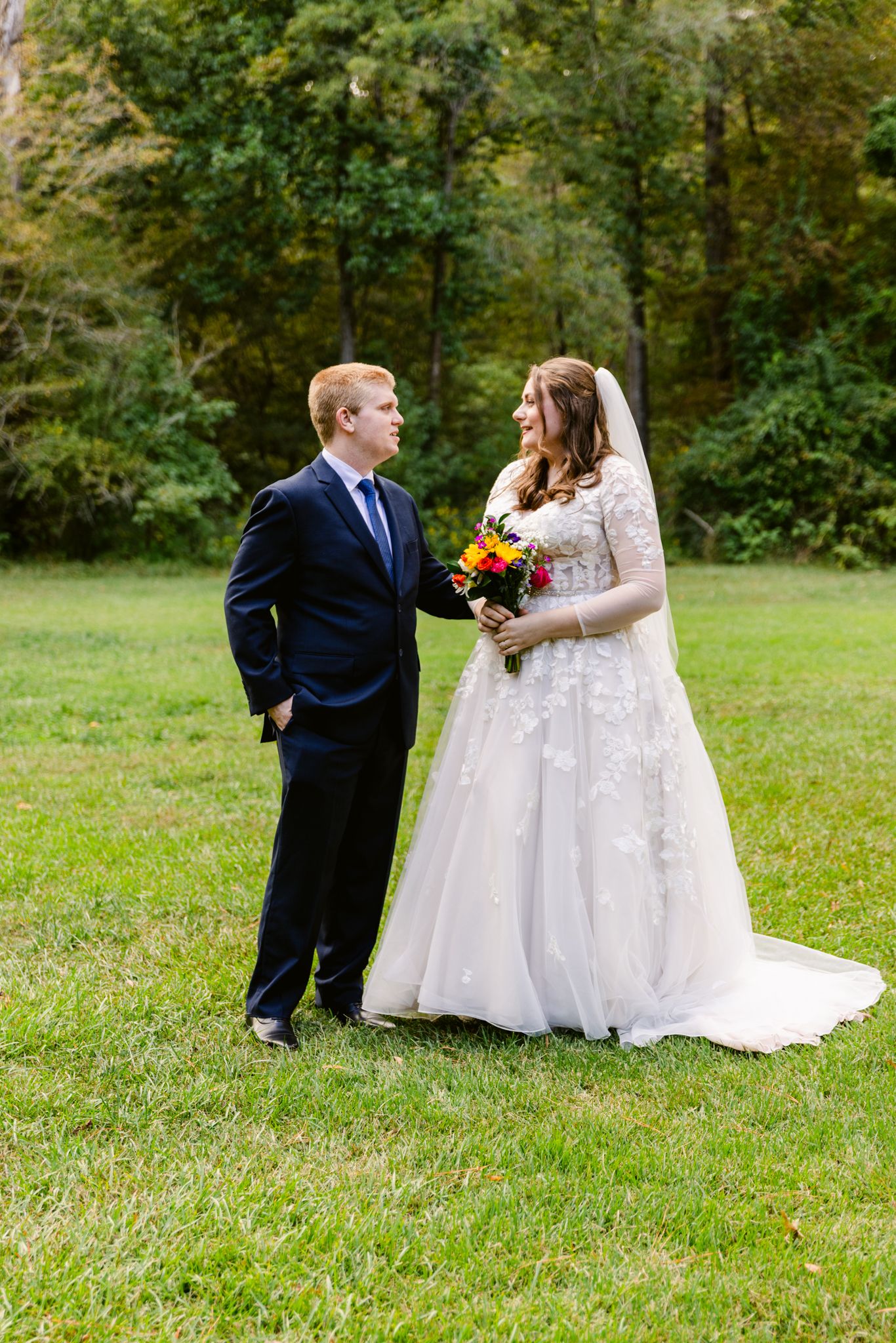 Wedding couple sharing a romantic moment on a grassy lawn during their outdoor autumn celebration.