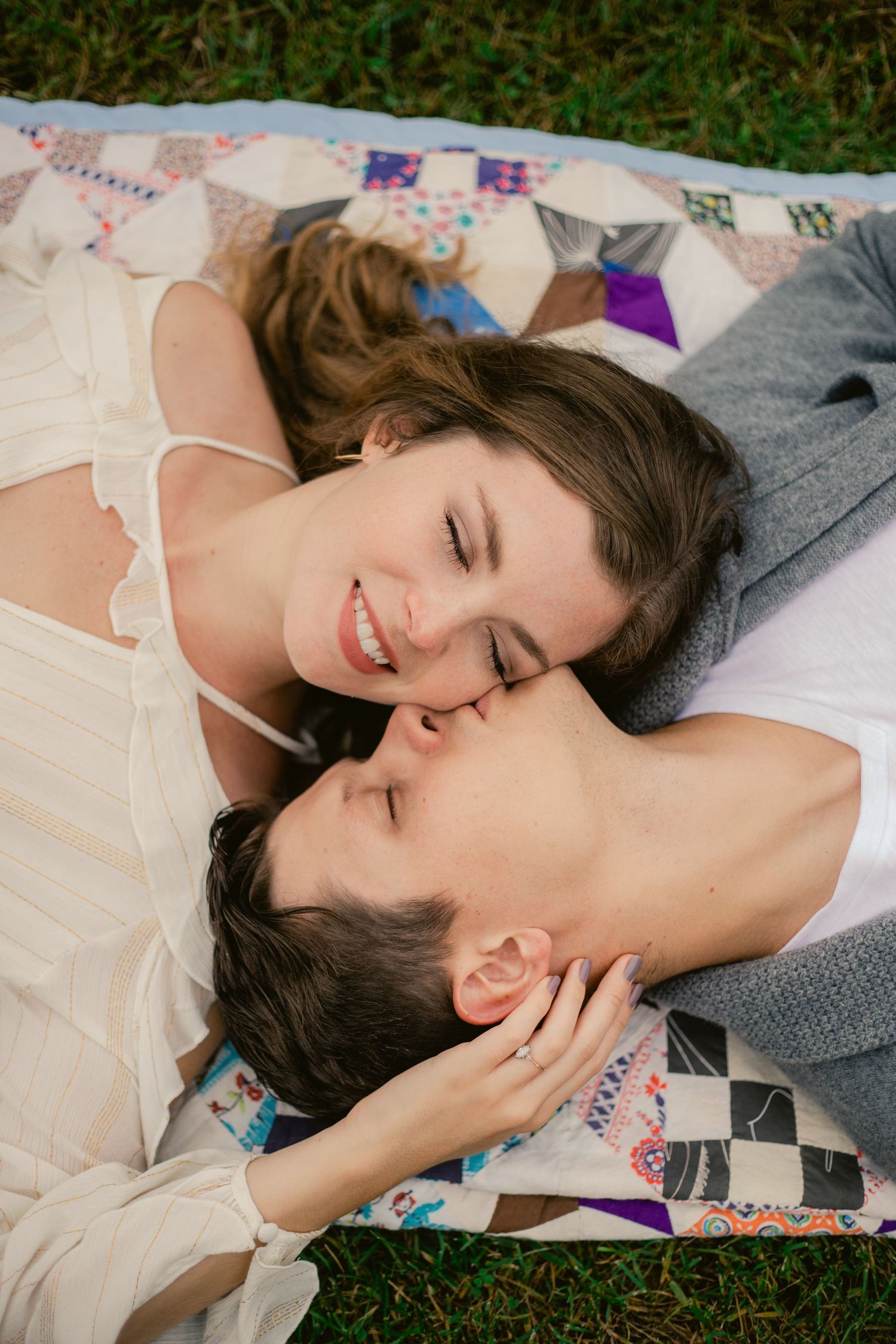 Intimate moment captured of couple lying close together on a quilt outdoors.