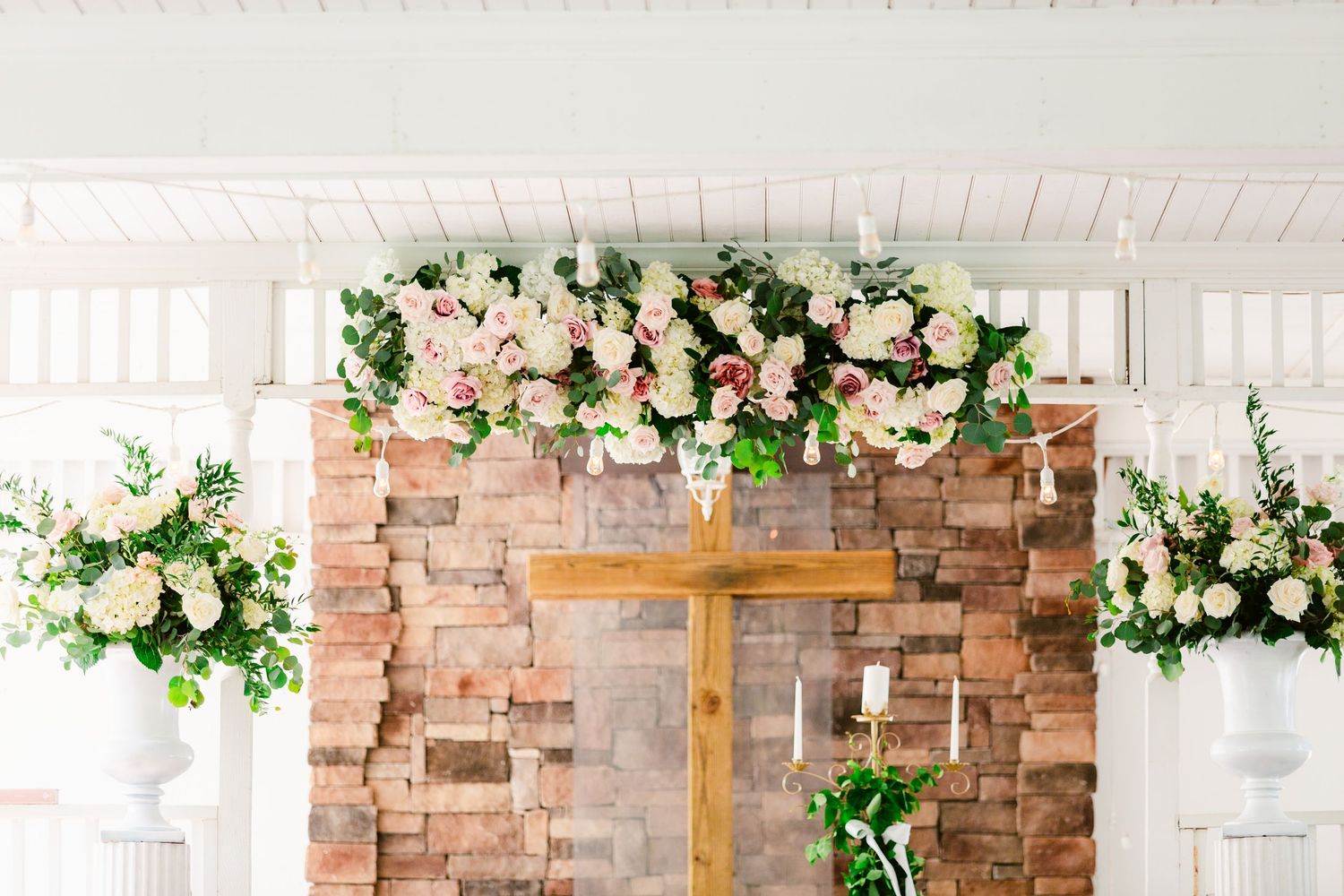 Rustic brick wall backdrop with white wood paneling and delicate floral arrangements creating an elegant event setting.