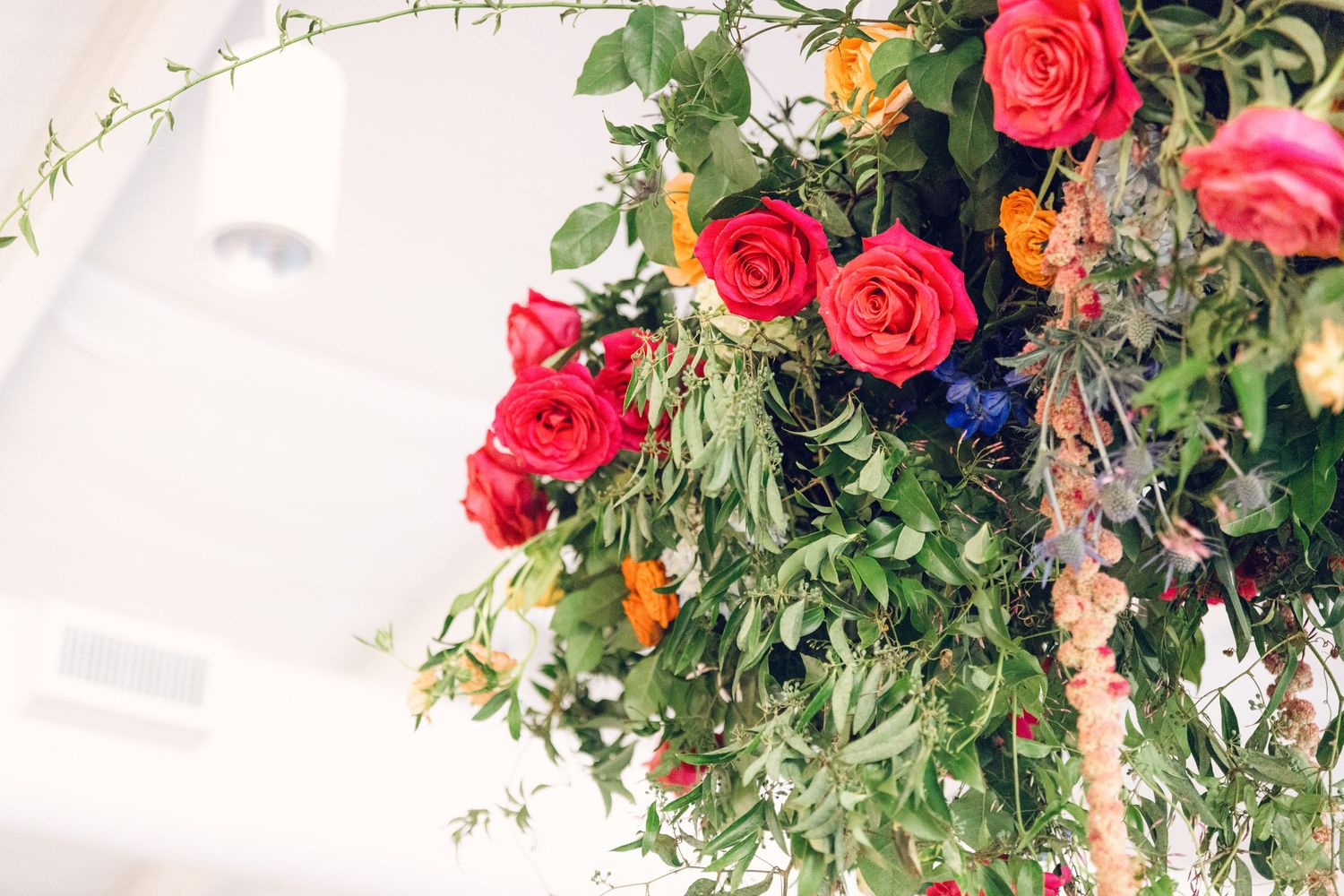 Vibrant red roses and greenery cascade down in a lush hanging floral arrangement.