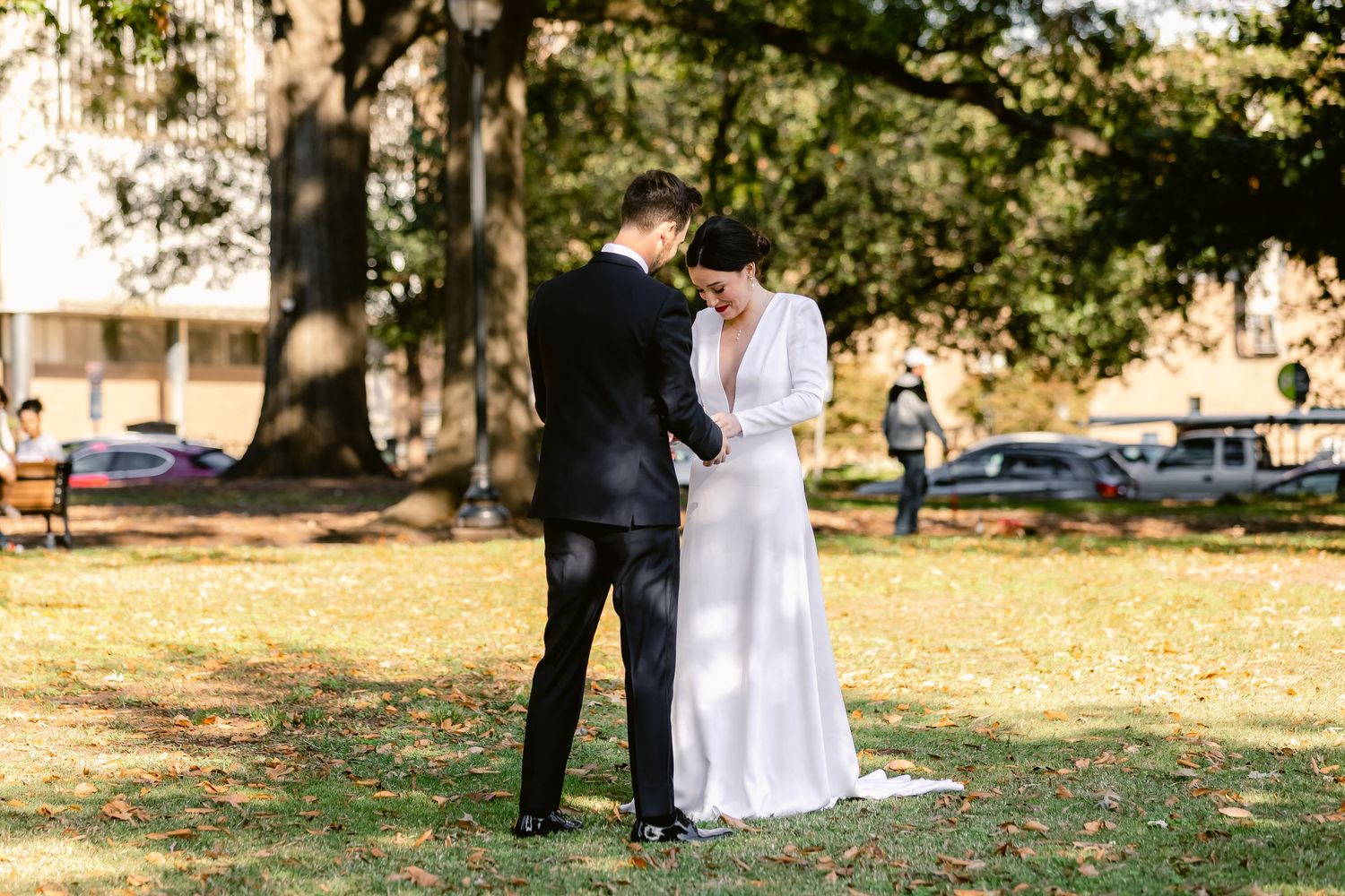 A couple in wedding attire embraces under autumn trees during an outdoor photo session.