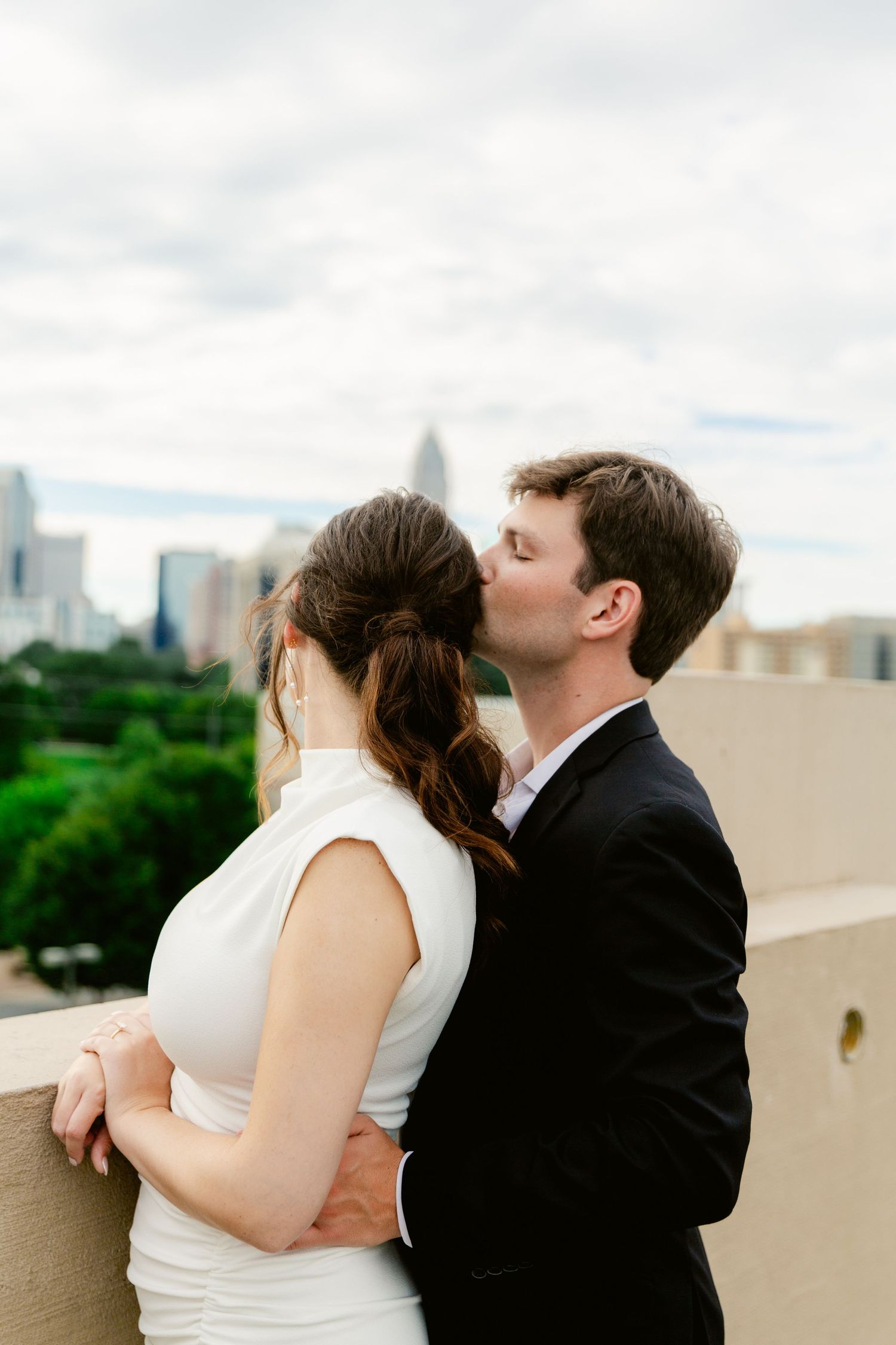 A romantic sequence of wedding photos showing a couple sharing a tender kiss against a city skyline backdrop.