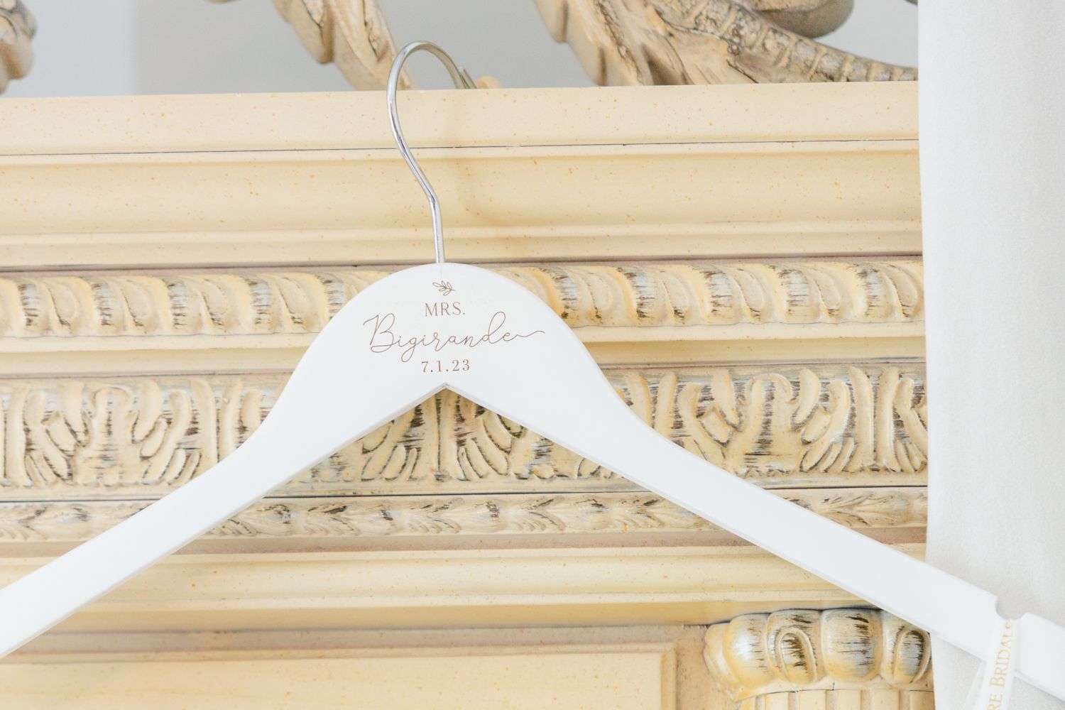 White plastic hangers displayed against an ornate cream-colored wall with decorative crown molding details.