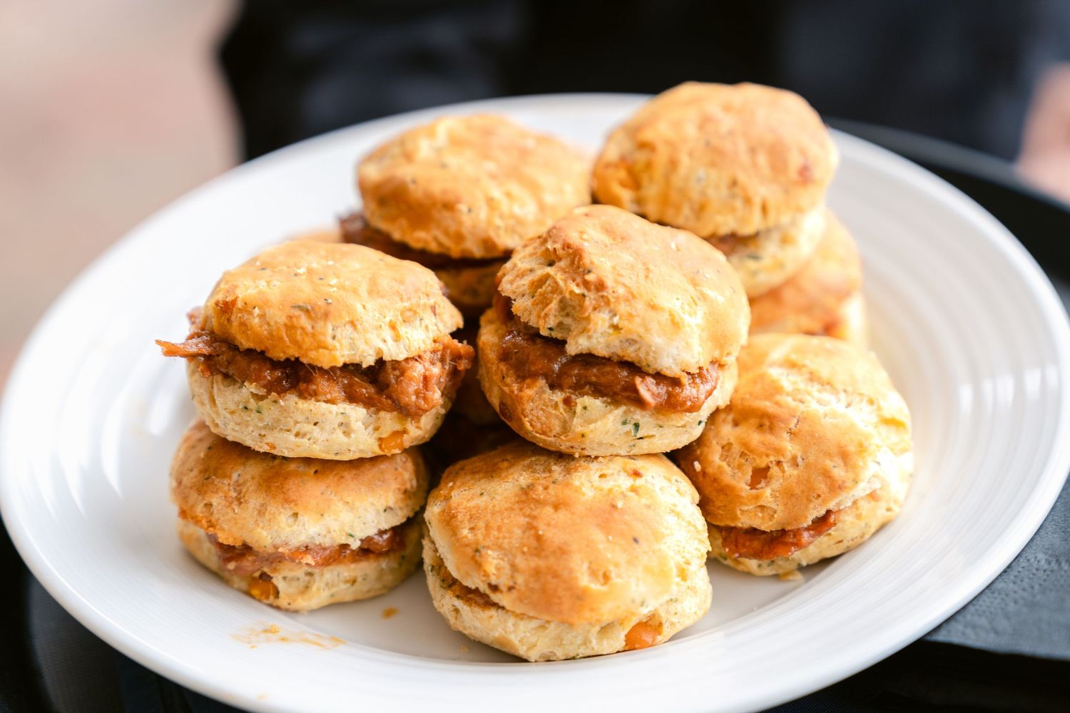Golden buttermilk biscuits stacked on white plates showing different stages of preparation and serving.