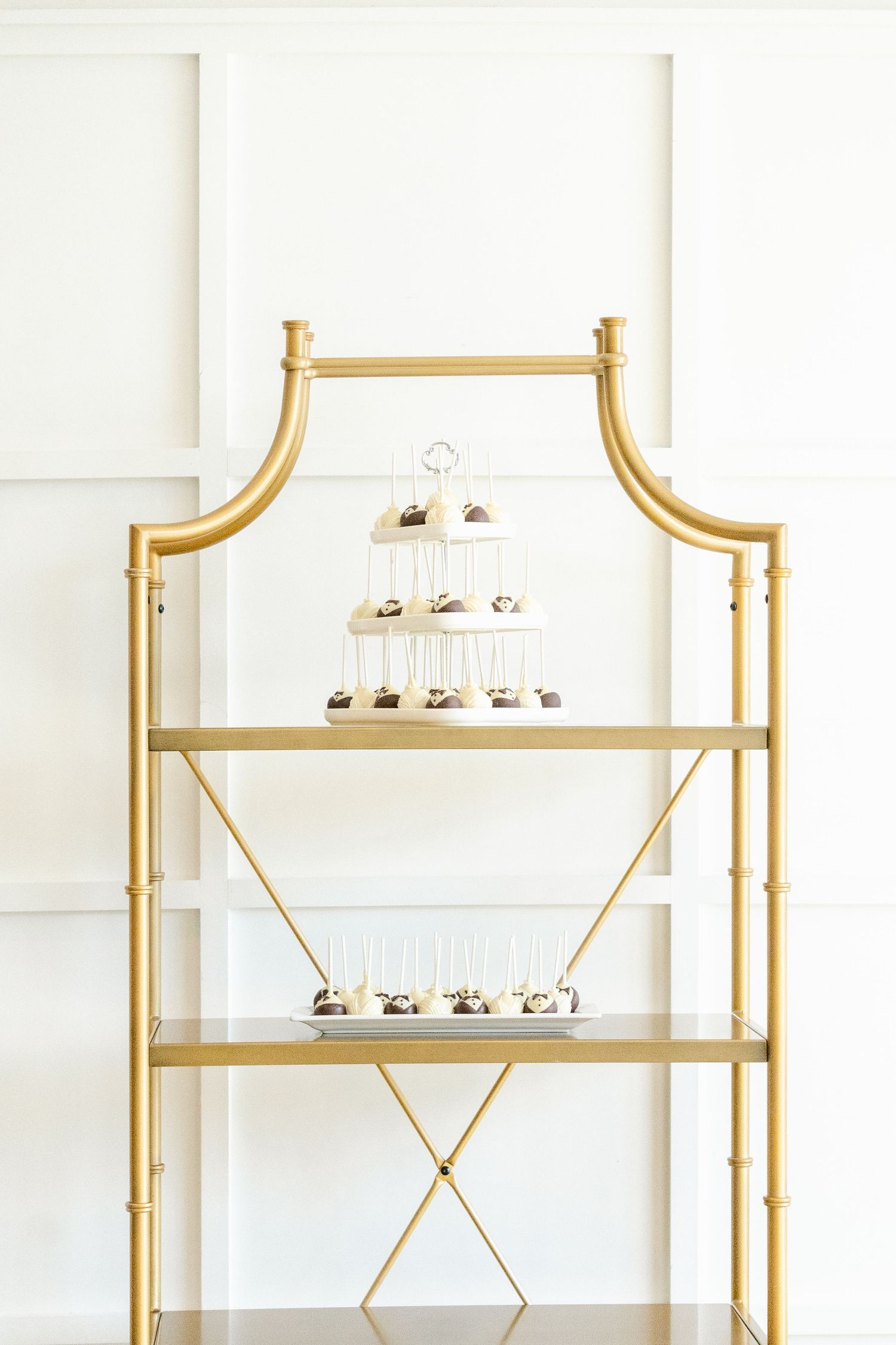 Gold and white modern shelving unit with geometric details and glass shelves displaying small decorative items.