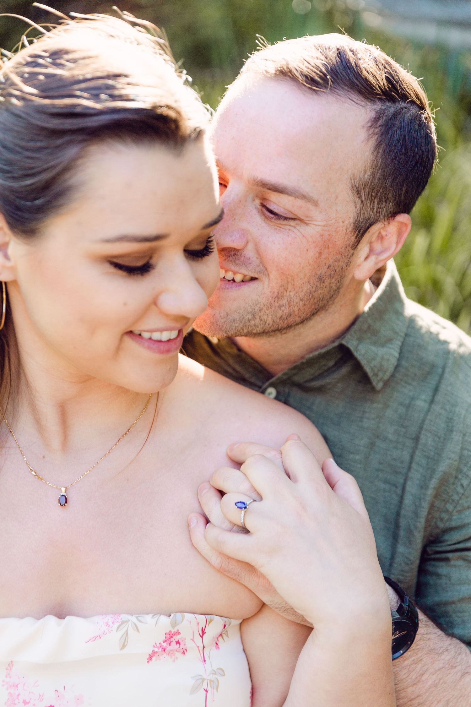 Romantic couple sharing intimate moments in a sunlit outdoor setting with soft natural lighting.