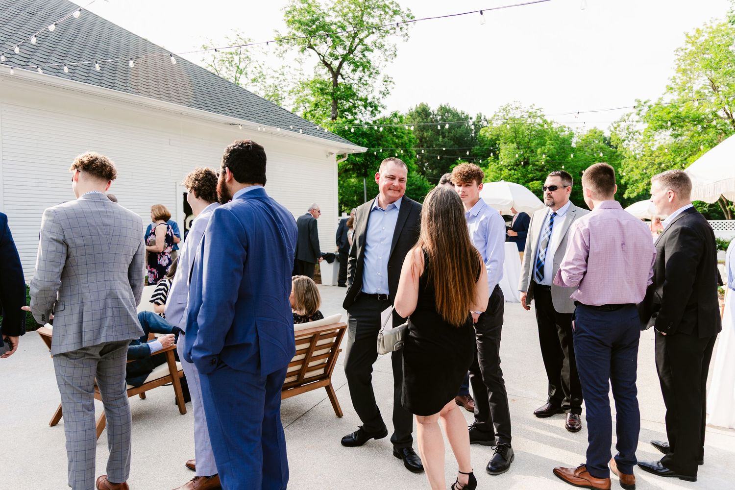 A group of well-dressed guests mingle and socialize at an outdoor event venue.