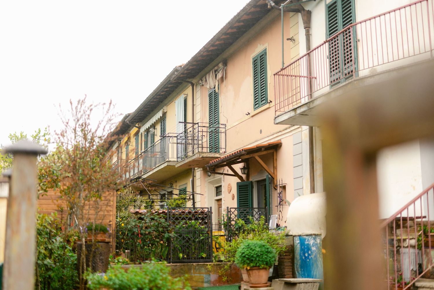 Modern townhouses with green shutters and orange balconies line a residential street in a suburban neighborhood.