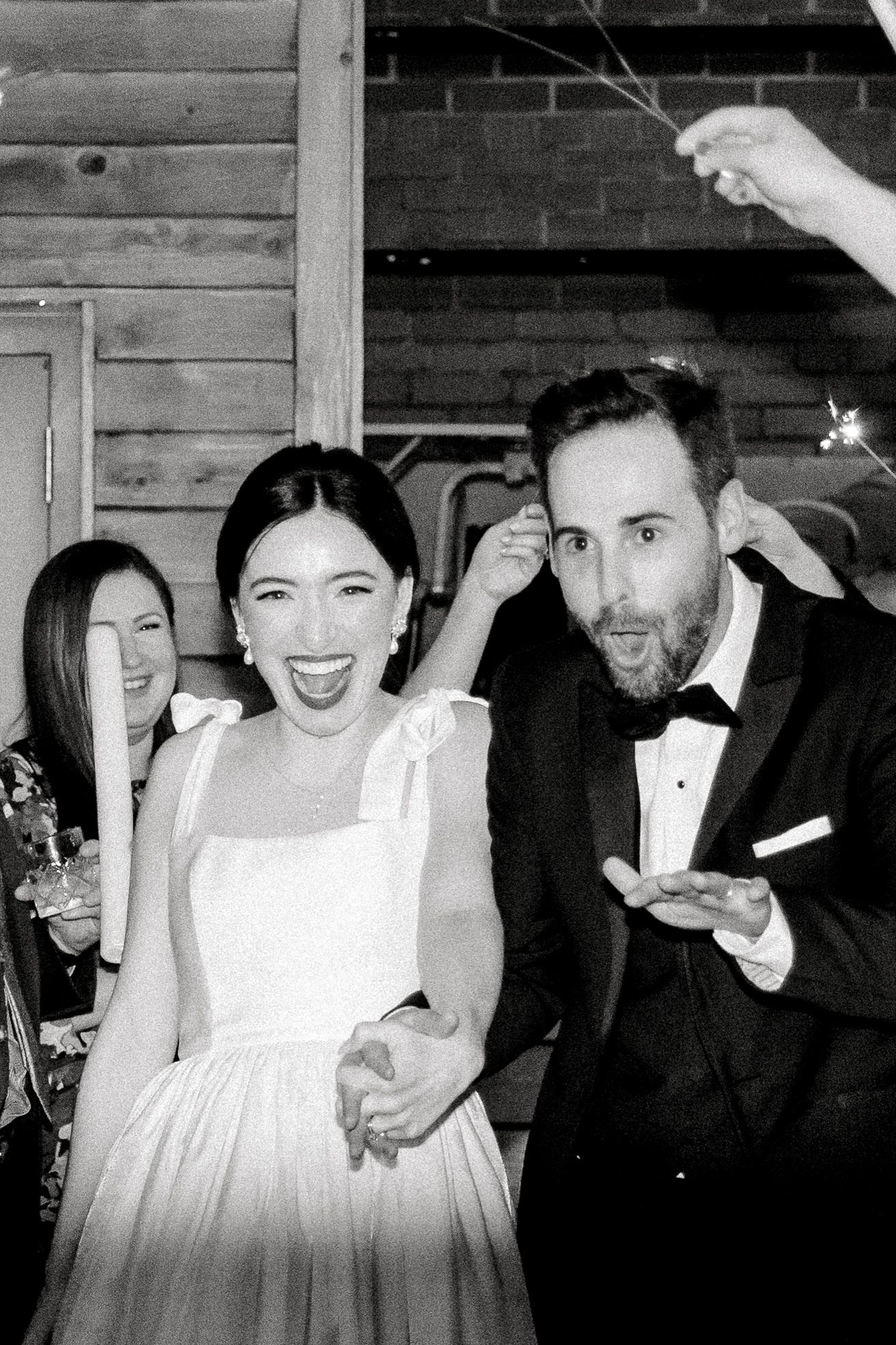Black and white photo sequence showing joyful moments at a formal wedding reception with candid laughter and celebrations.