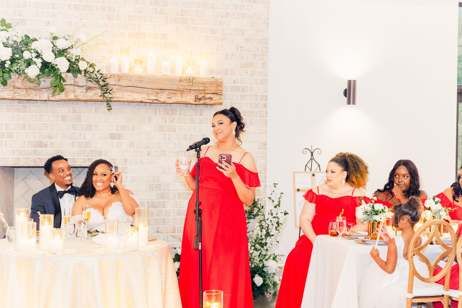 Wedding party members in red dresses and formal attire celebrate at an elegant indoor reception.