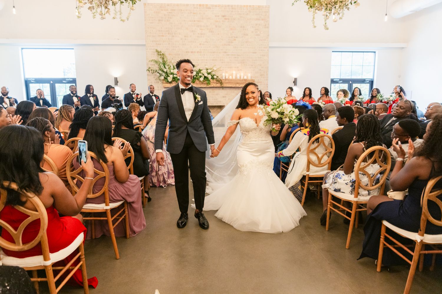 Wedding guests seated in rows of wooden chairs in a bright modern venue.