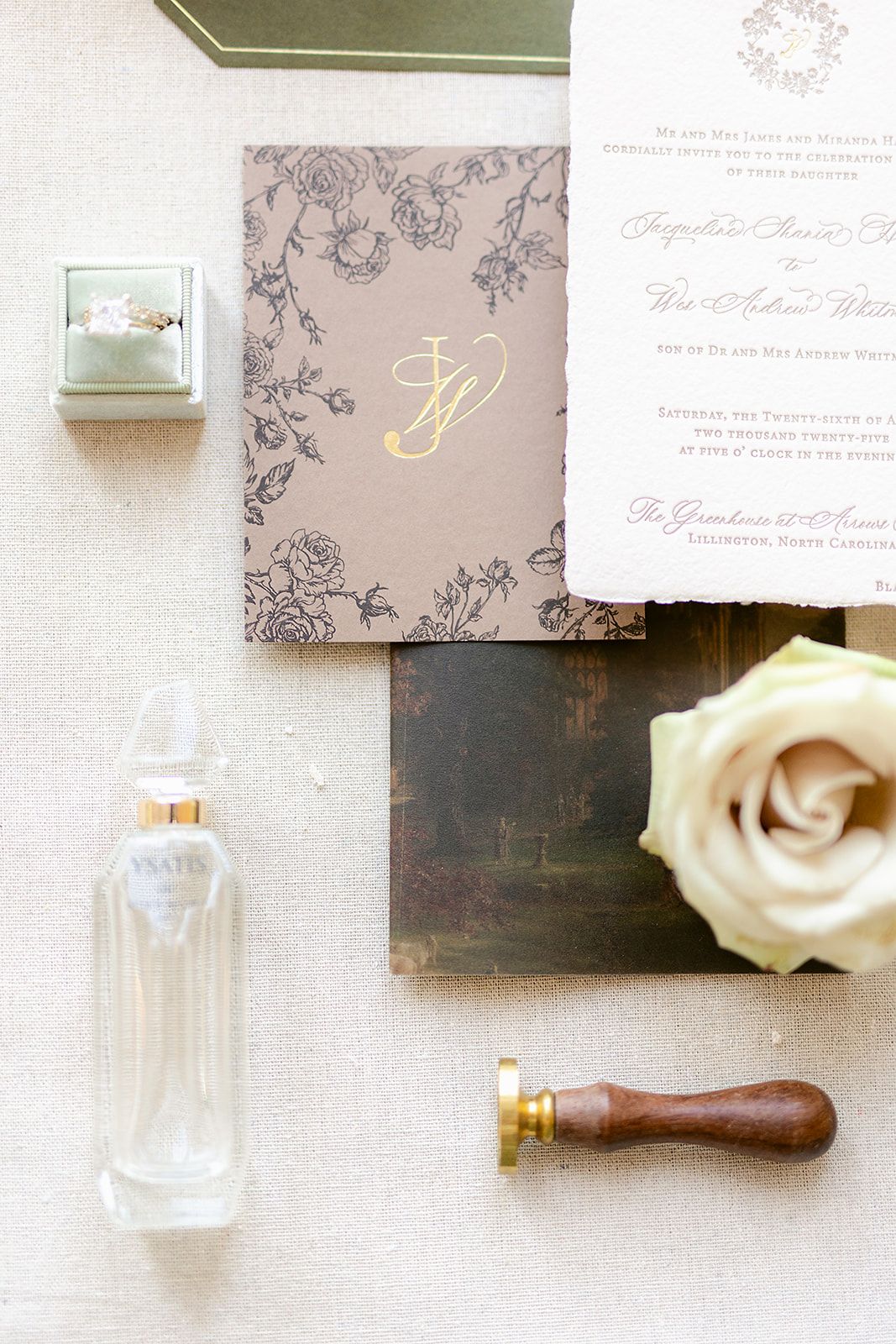 Elegant wedding stationery and decor items including invitations, roses, and wax seals arranged on a neutral background.