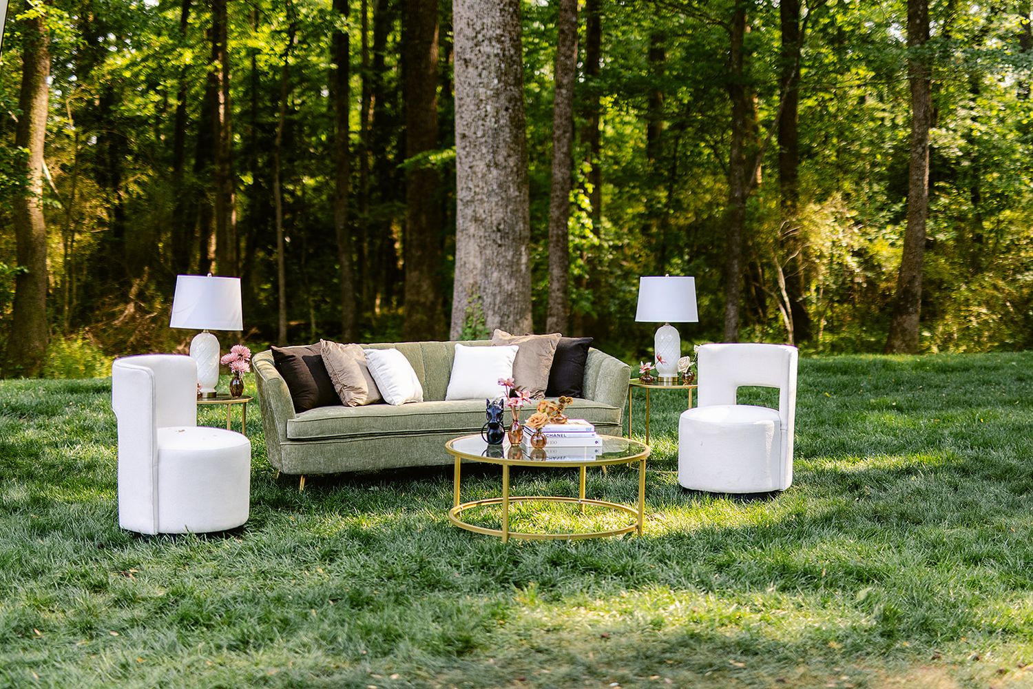 White lounge furniture arranged in an outdoor woodland setting creates an elegant seating area for a garden event.