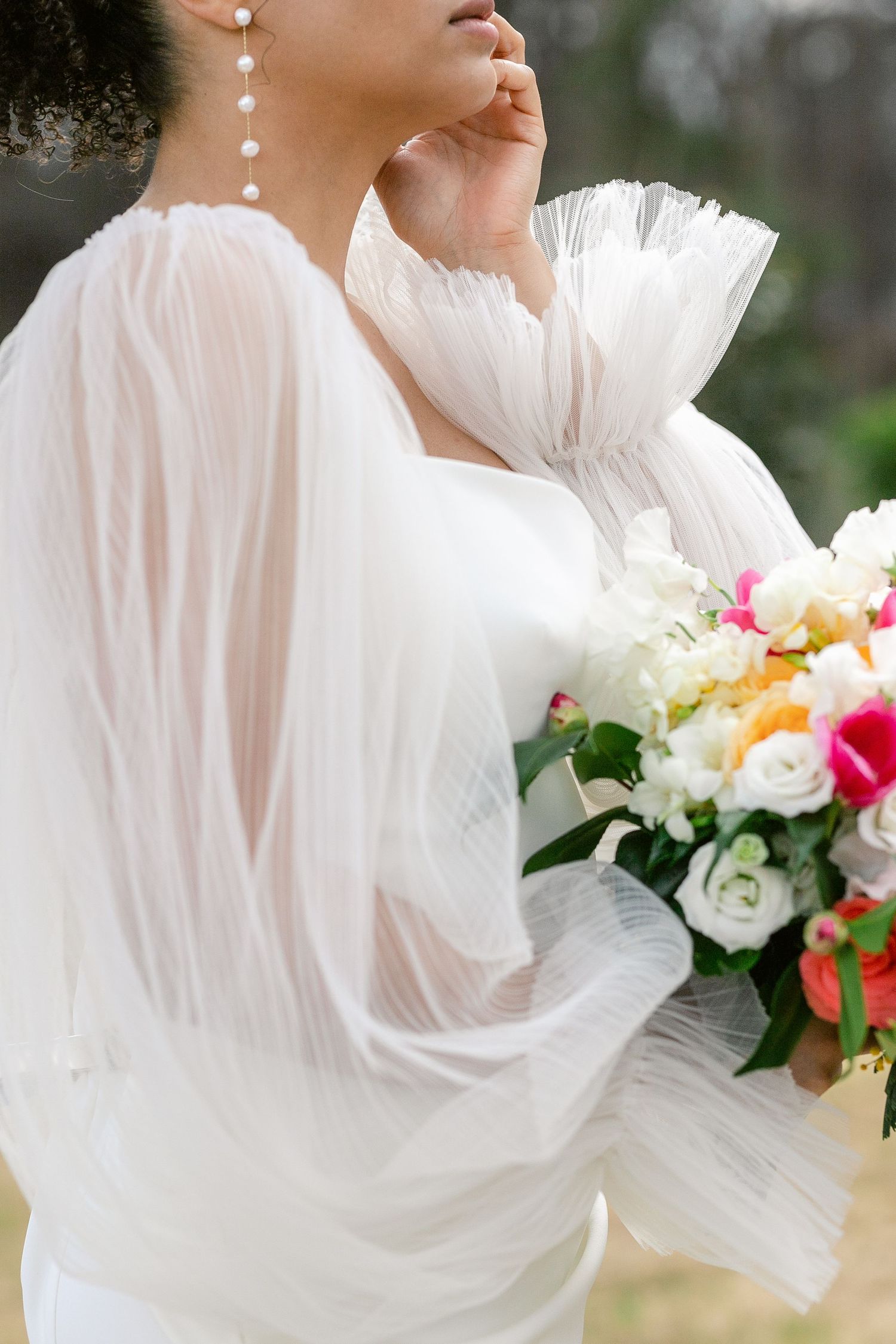 Elegant bridal portrait showcasing dramatic sheer puff sleeves and a vibrant multicolored bouquet.
