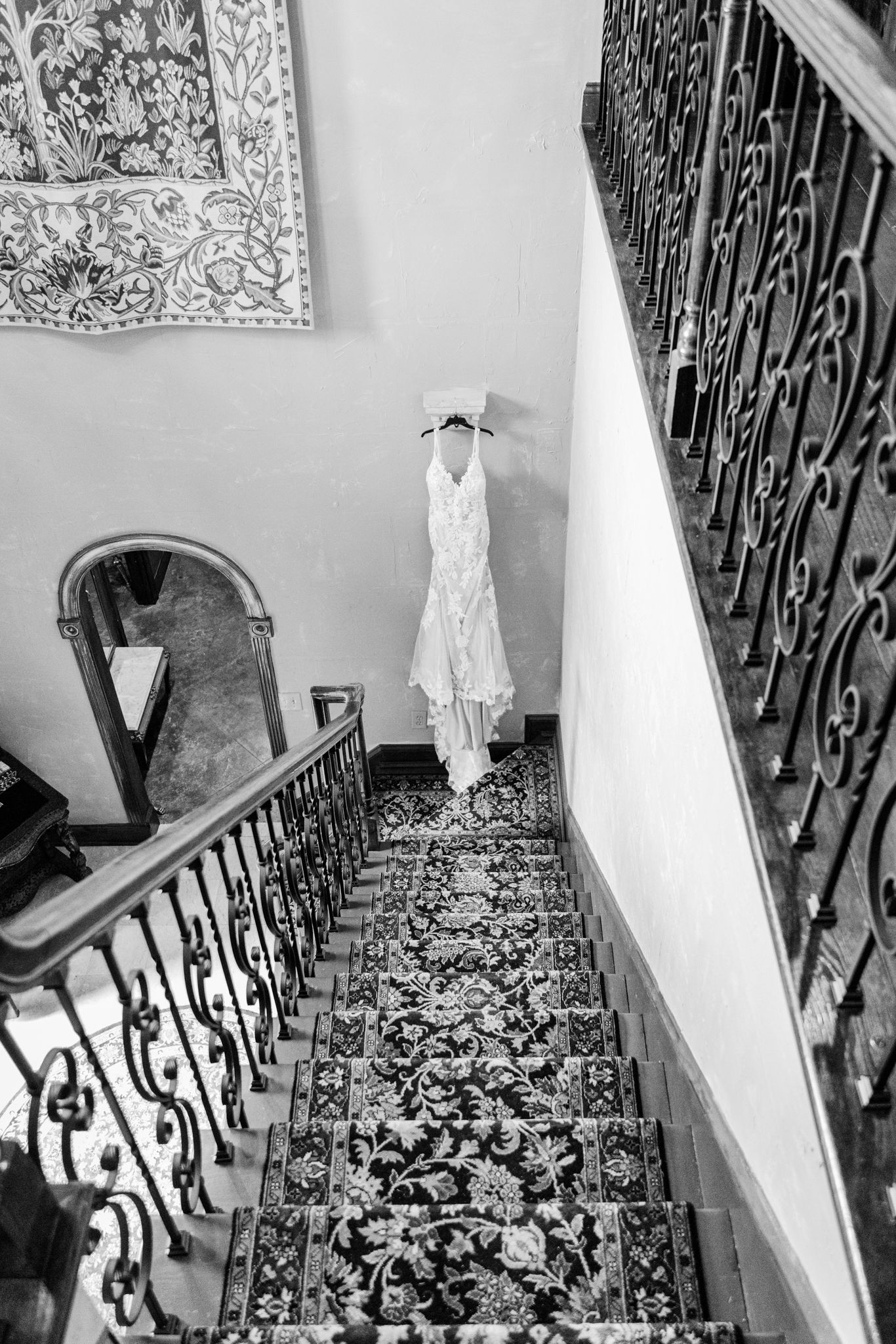 Ornate black wrought iron stair railing with decorative scrollwork leads up white-walled staircase in residential interior.