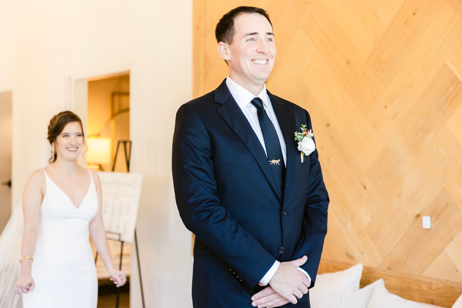 A couple during their first look moment at a wedding with a modern chevron wall backdrop.