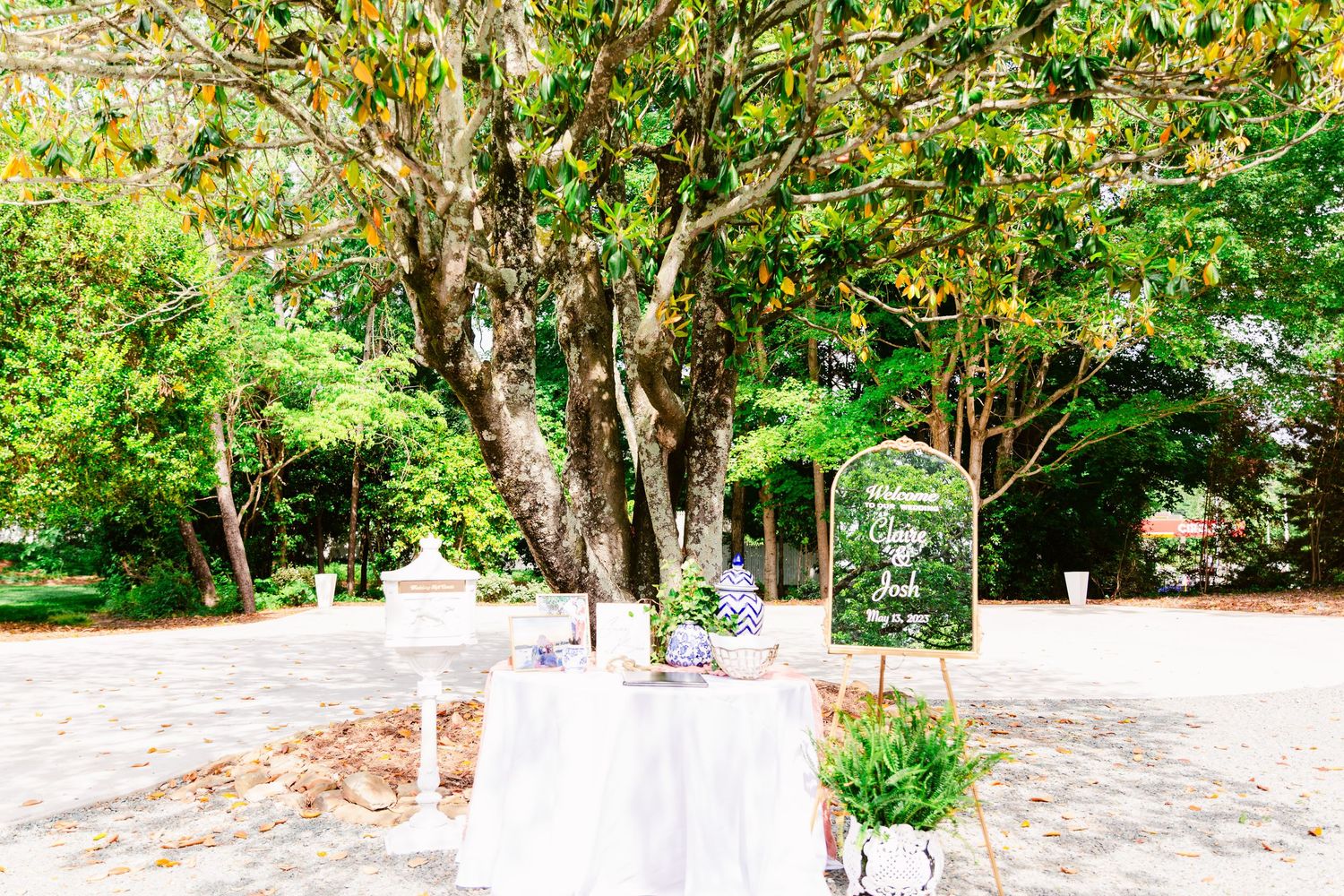 Lush garden path with mature trees and landscaping leading to white building entrance.