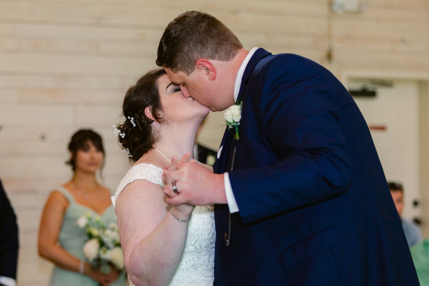 A romantic wedding ceremony moment captured in an indoor venue with wooden paneled walls.