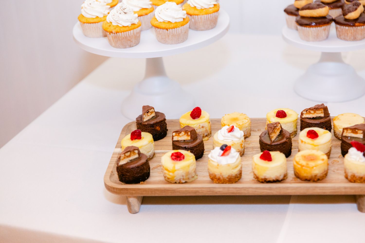 Assorted mini cupcakes and pastries displayed on wooden serving boards at a dessert table.