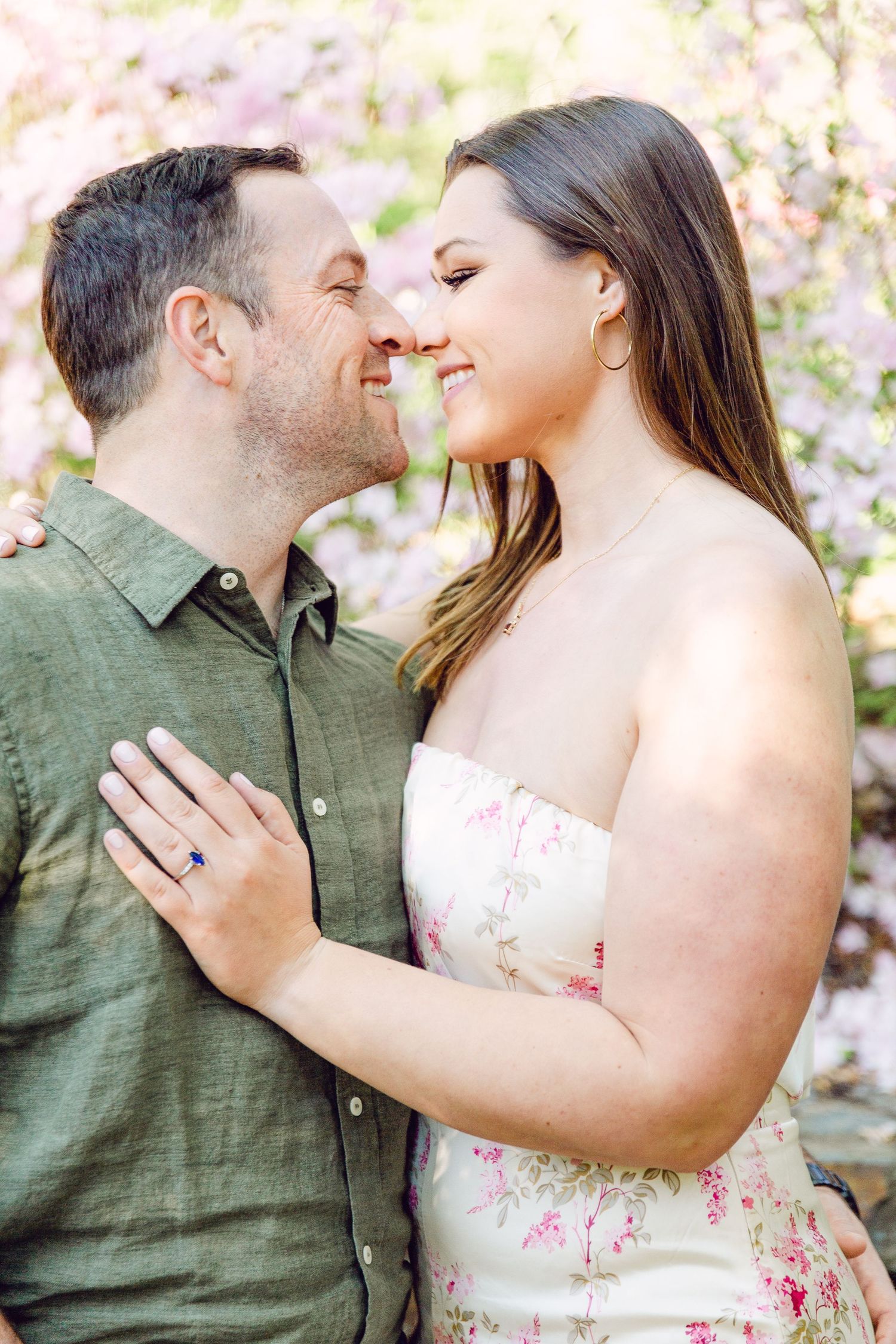 A romantic engagement photoshoot series with a couple embracing in front of pink cherry blossoms.