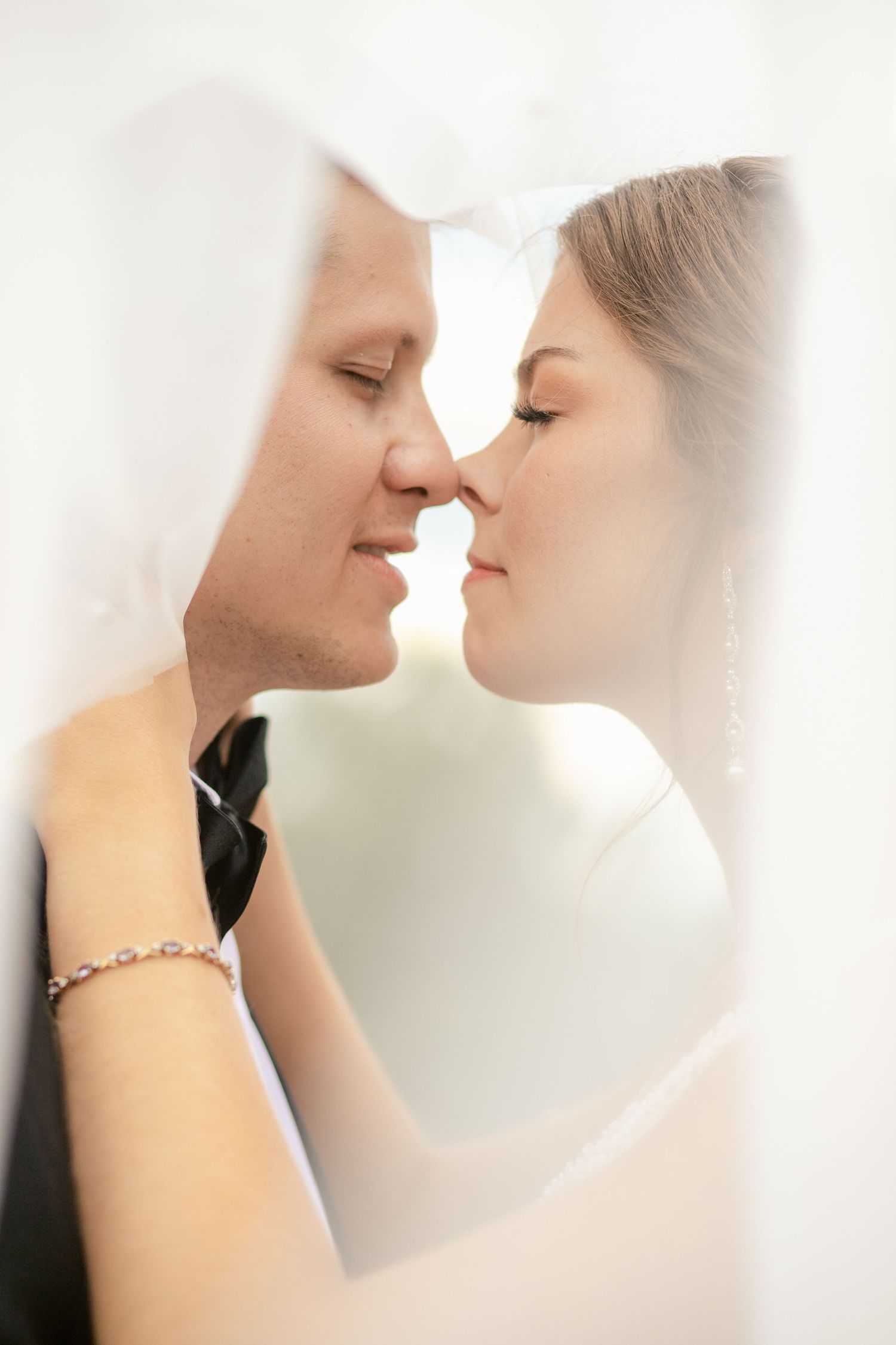Romantic close-up of a couple sharing an intimate moment under a delicate white veil.
