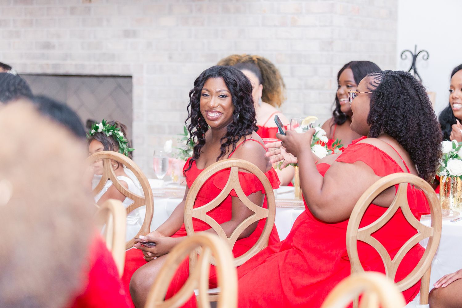 Bridesmaids in red dresses celebrate during wedding reception.