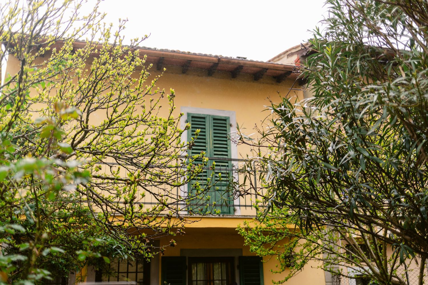 Mediterranean style houses with green shutters and terracotta roofs under cloudy skies.