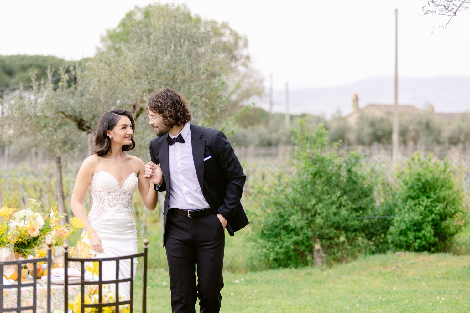 A couple in wedding attire walks through a lush garden setting during their romantic outdoor photo session.