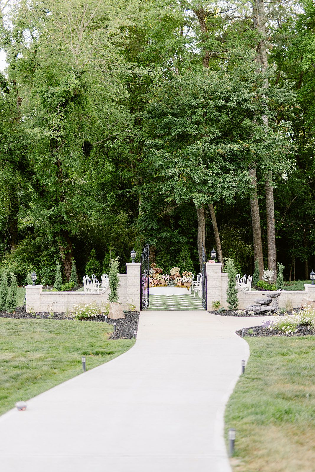 A white curved wall structure with landscaped greenery creates a modern backdrop in an outdoor garden setting.