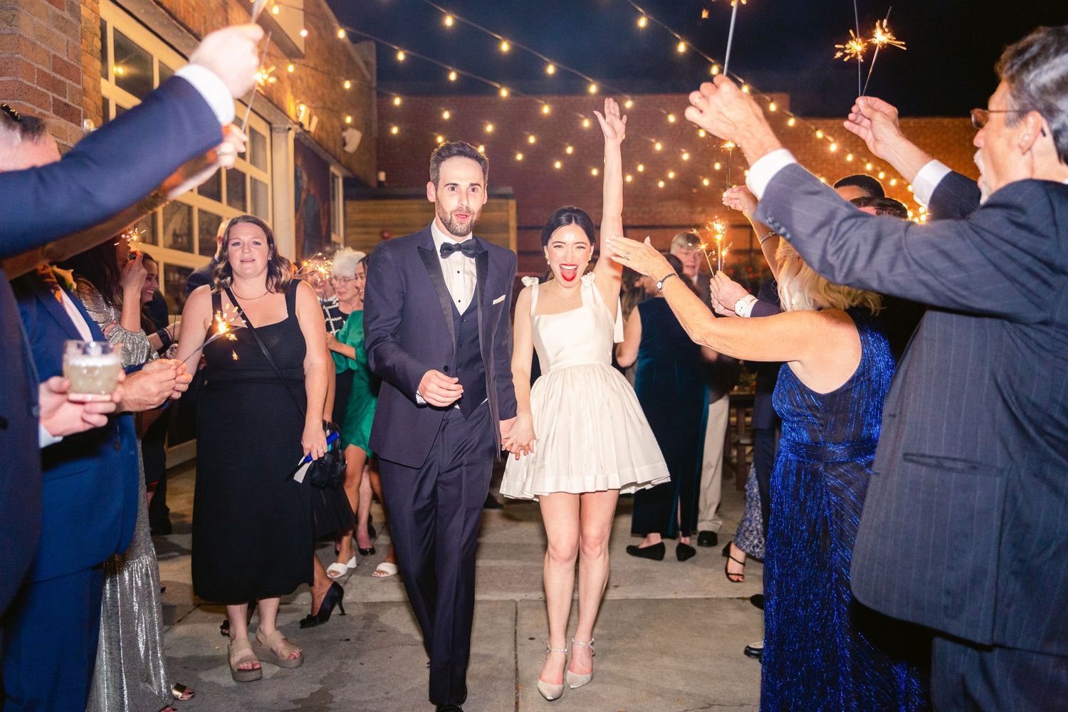 Outdoor wedding celebration at night with string lights creating a romantic ambiance.