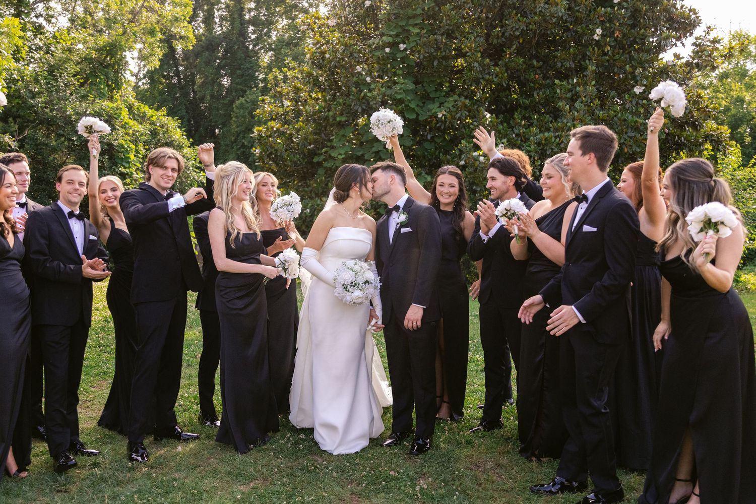 Wedding party plays a fun game of catch with a beach ball in an outdoor garden setting.