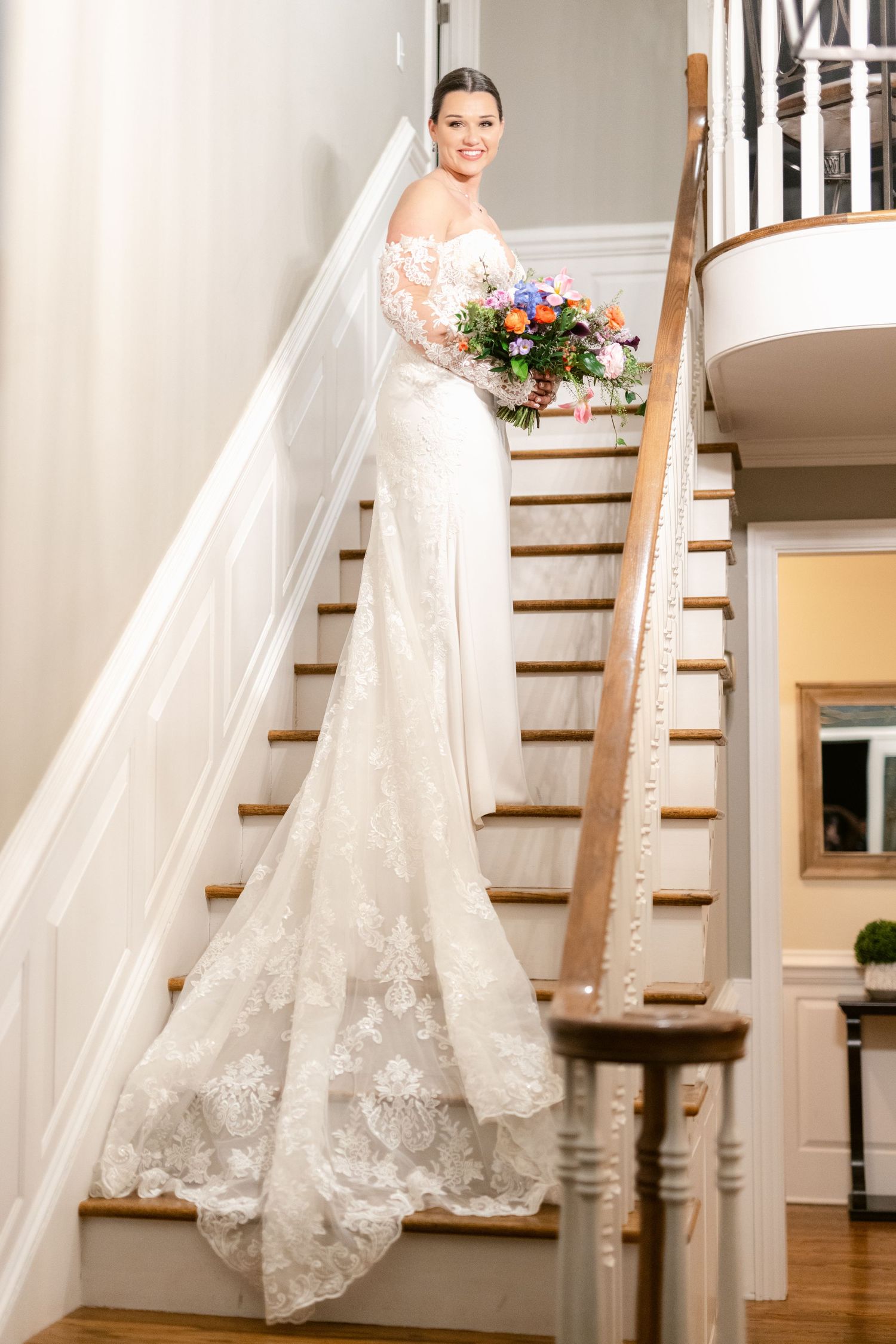 Beautiful wedding gown with lace details and flowing train displayed on an elegant white staircase.