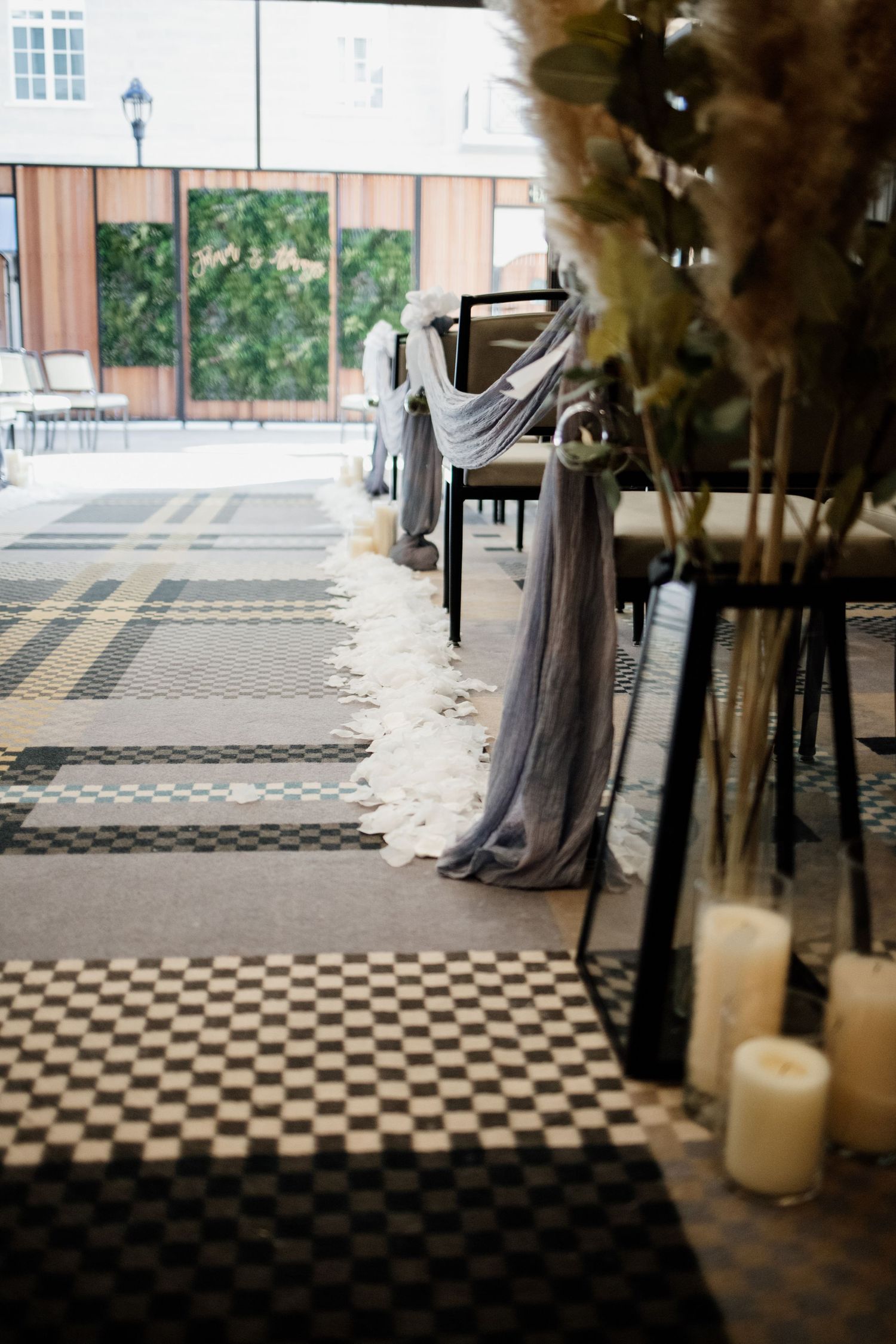 Wedding aisle with checkered floor and draped fabric chair decorations.