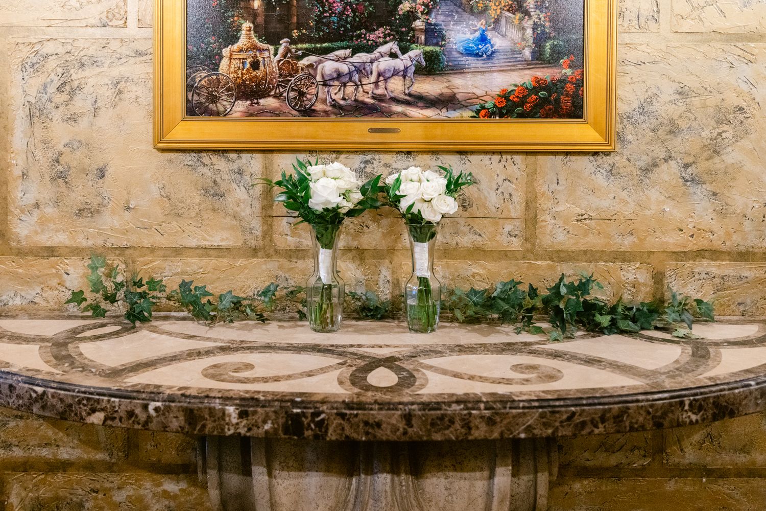 Rustic stone wall with decorative framed artwork and greenery creating an elegant outdoor gallery setting.