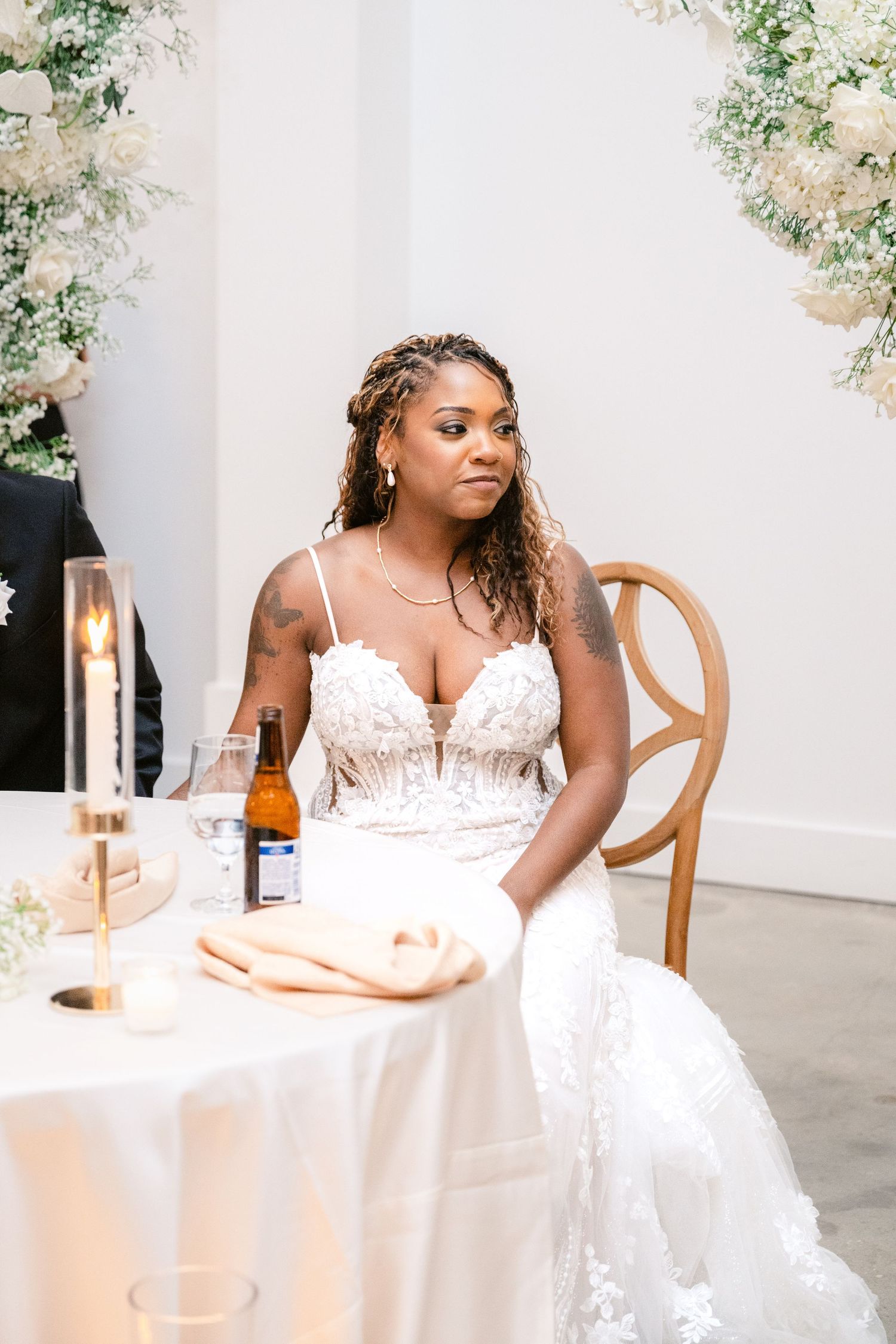 A person in a white wedding dress seated at an elegantly decorated reception table.
