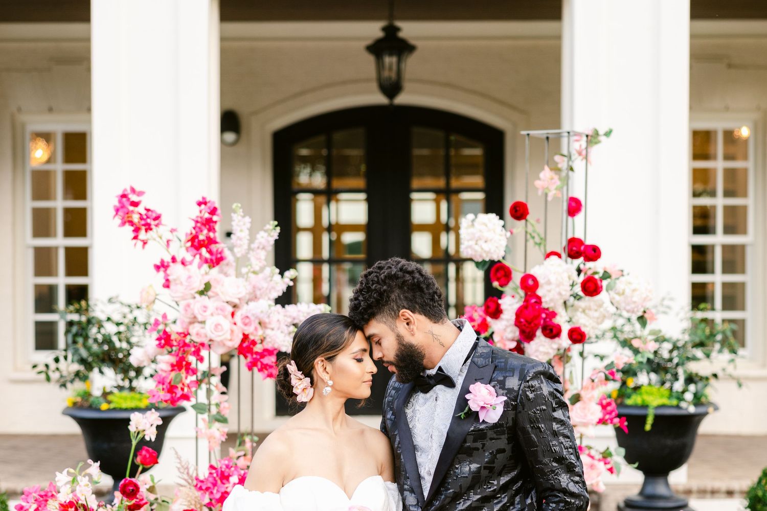 Outdoor wedding venue decorated with pink floral arrangements and white columns.