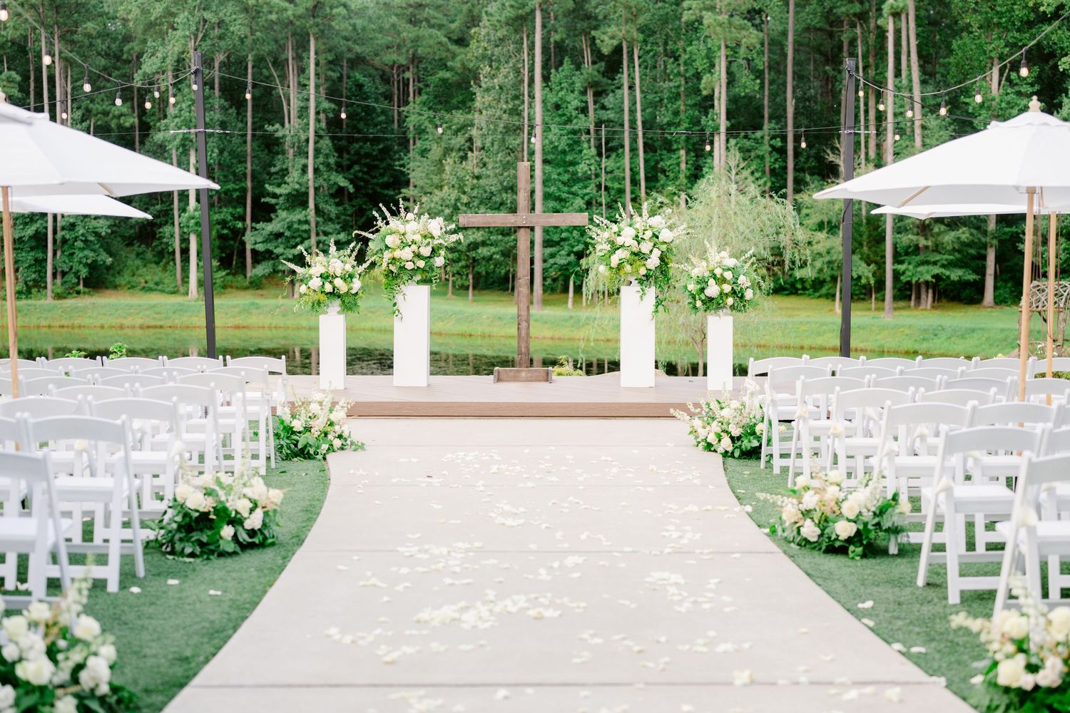 White garden chairs arranged in rows on a lush green lawn for an elegant outdoor wedding ceremony setup.