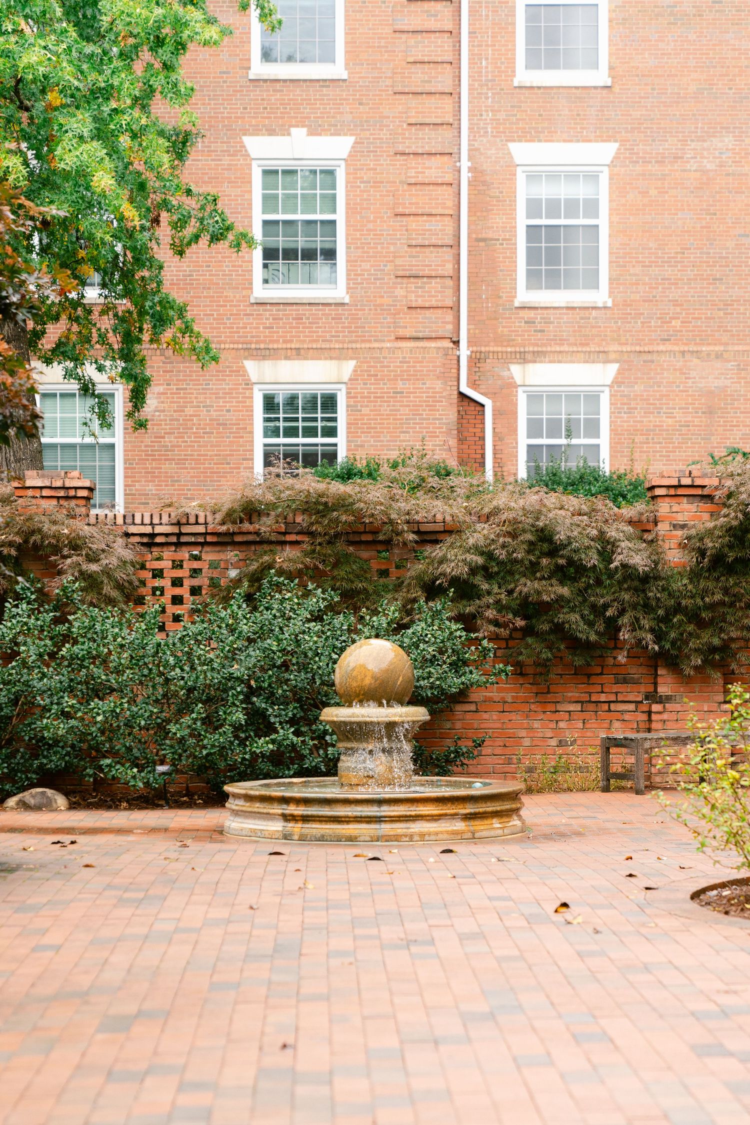 Brick courtyard with paved walkway and landscaping features surrounded by traditional architecture.