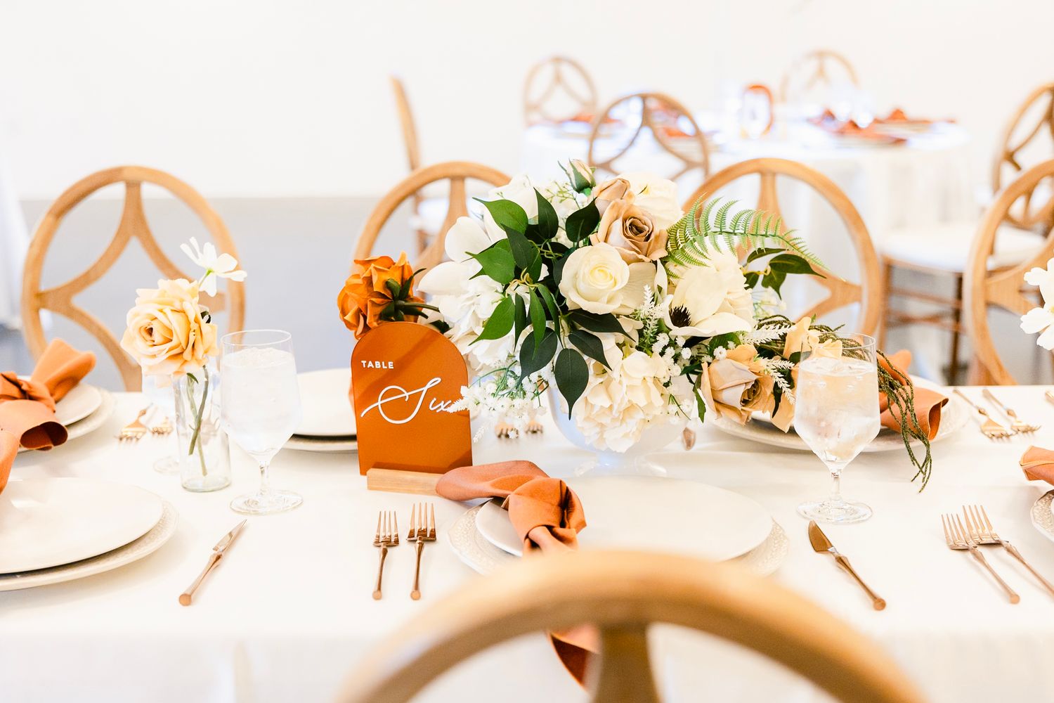 Elegant white and gold table settings with floral arrangements and candles create a luxurious wedding reception atmosphere.