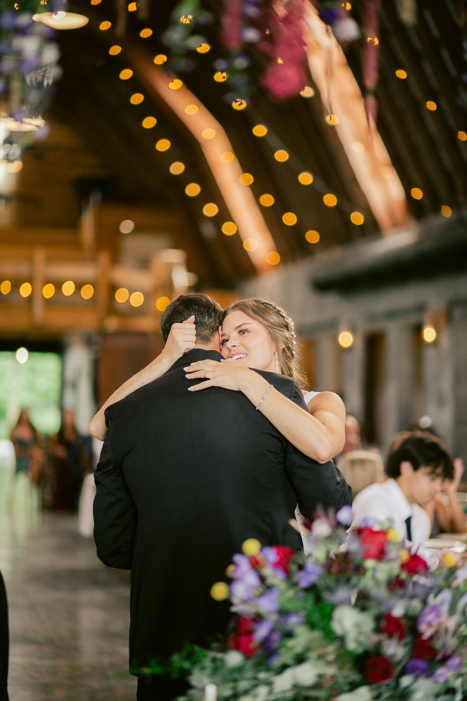 A couple embracing during an intimate dance beneath string lights at their wedding reception.