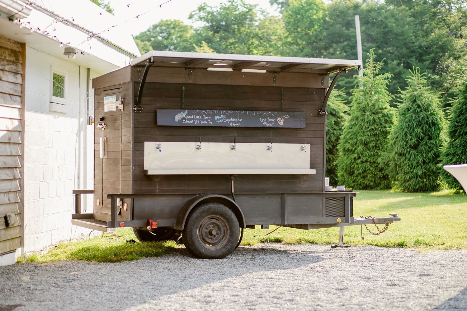 Mobile food truck parked outside with serving window and rustic wood exterior.