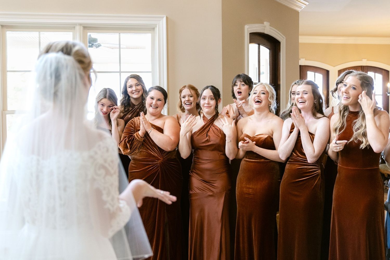 Bridesmaids in matching brown dresses pose during wedding preparations.
