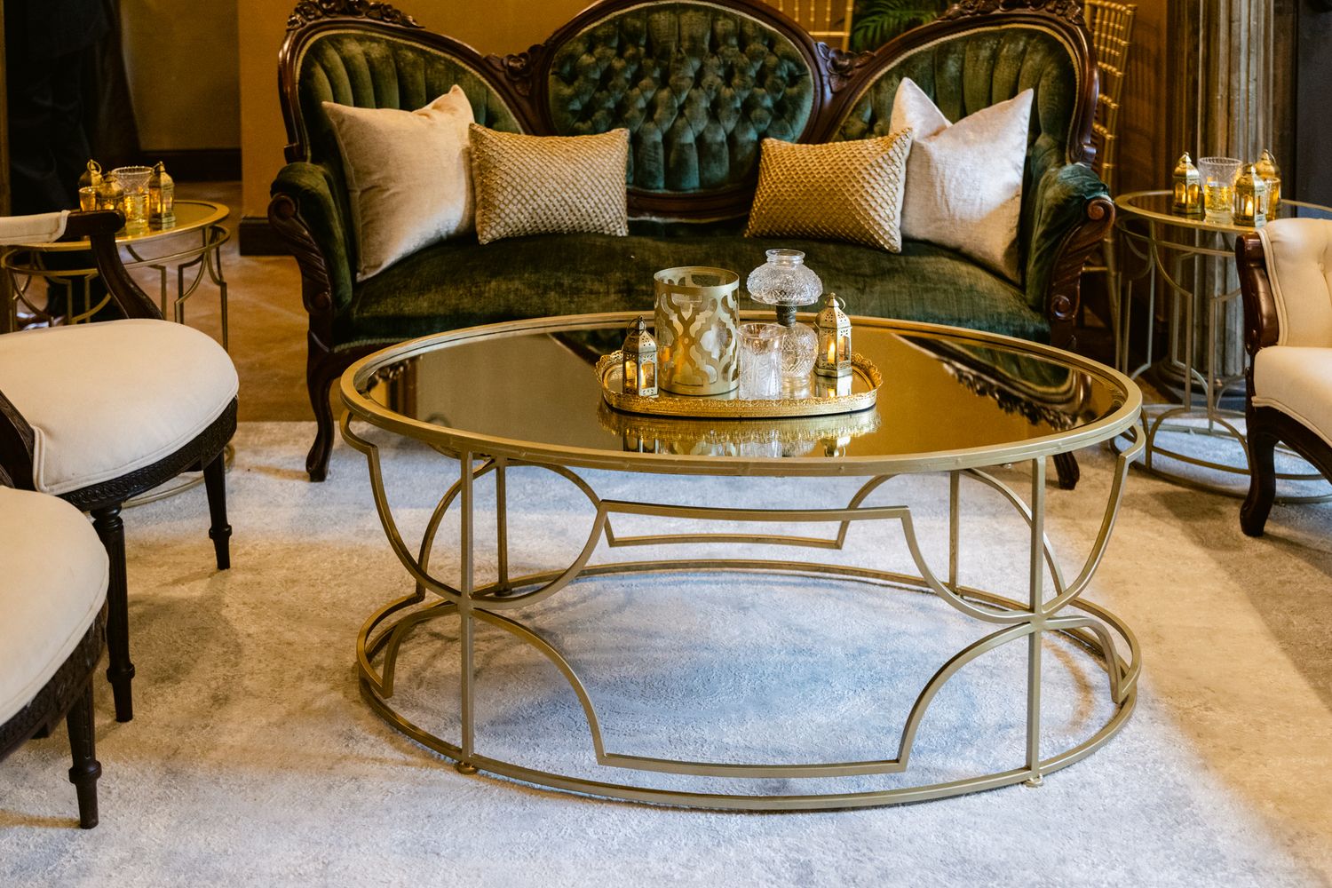 Elegant glass and metal round coffee table with curved legs displayed in a luxurious living room setting.