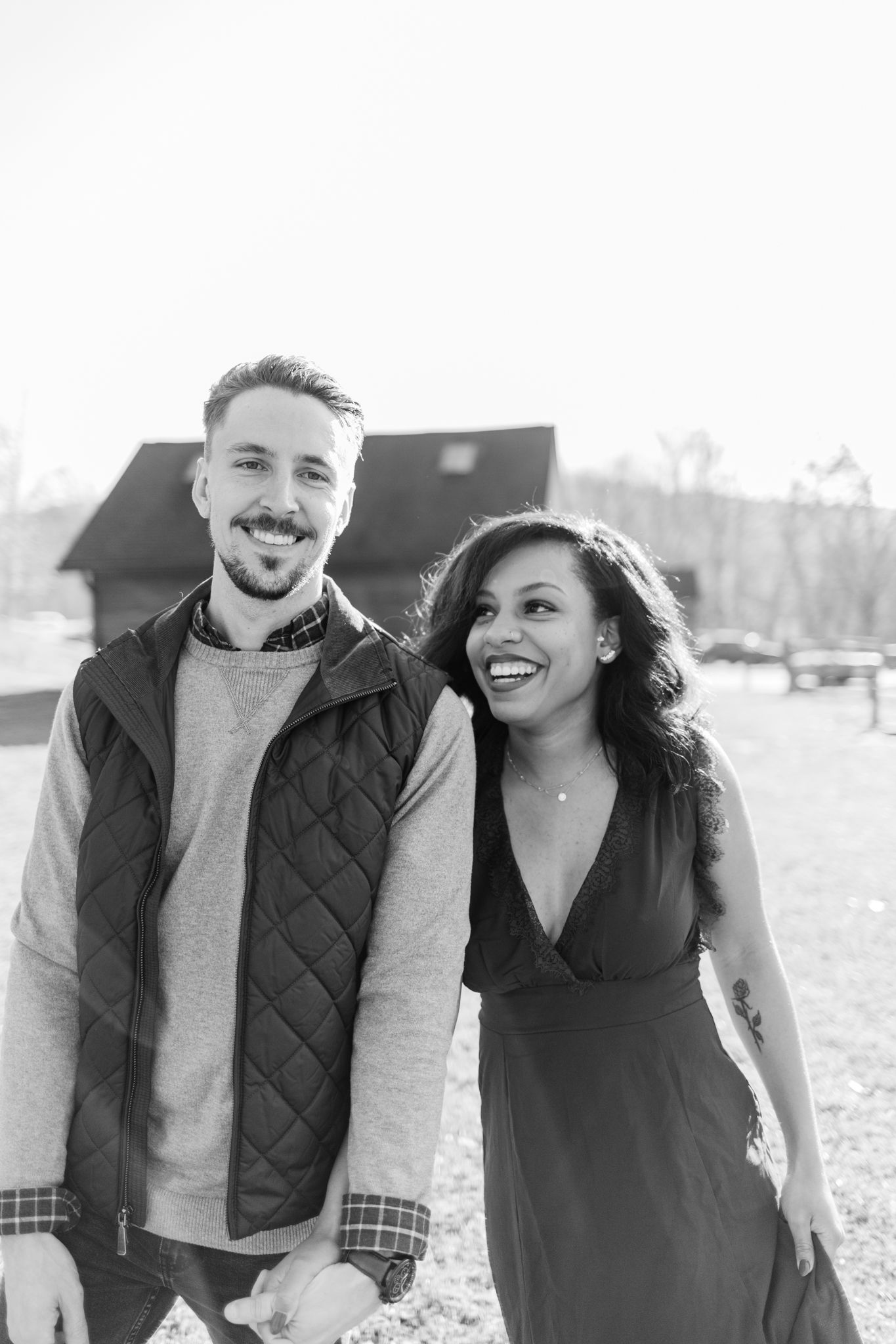 A couple laughs and embraces while taking outdoor portraits in winter clothing.