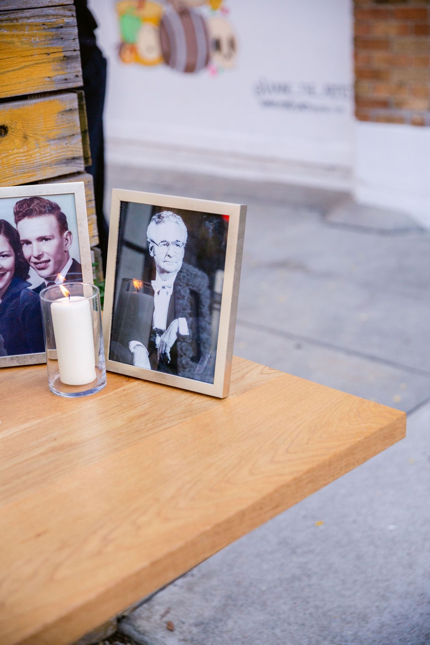 Vintage black and white photographs displayed on a wooden shelf with a white candle.