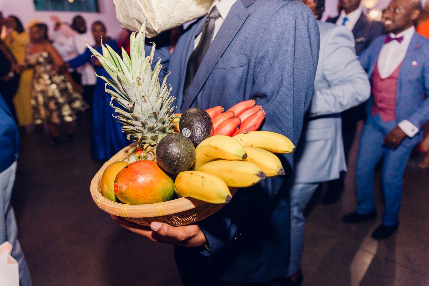 Wedding guests holding tropical fruits and snacks during reception festivities.