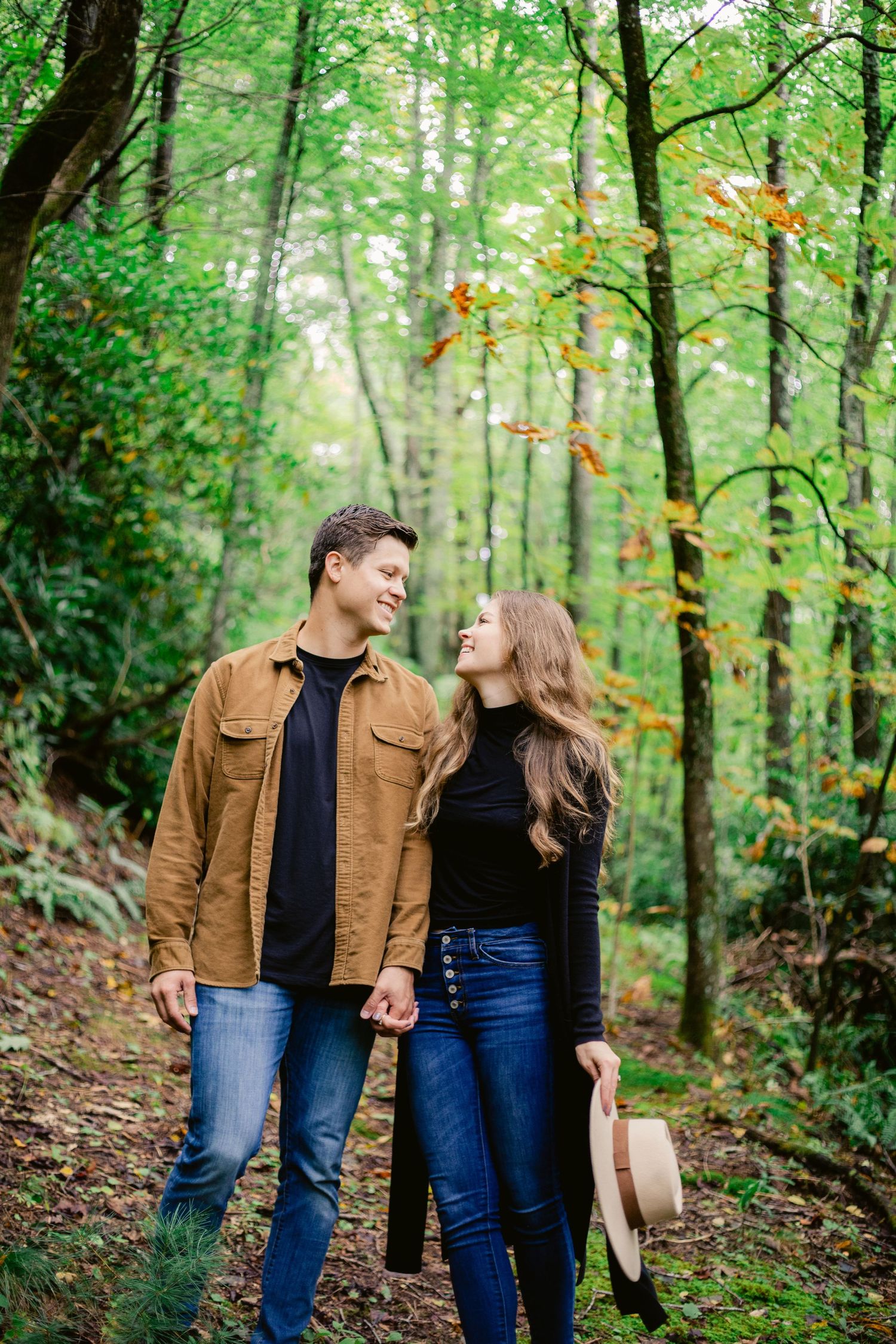 Couple enjoying an autumn day on a wooded trail wearing casual attire.